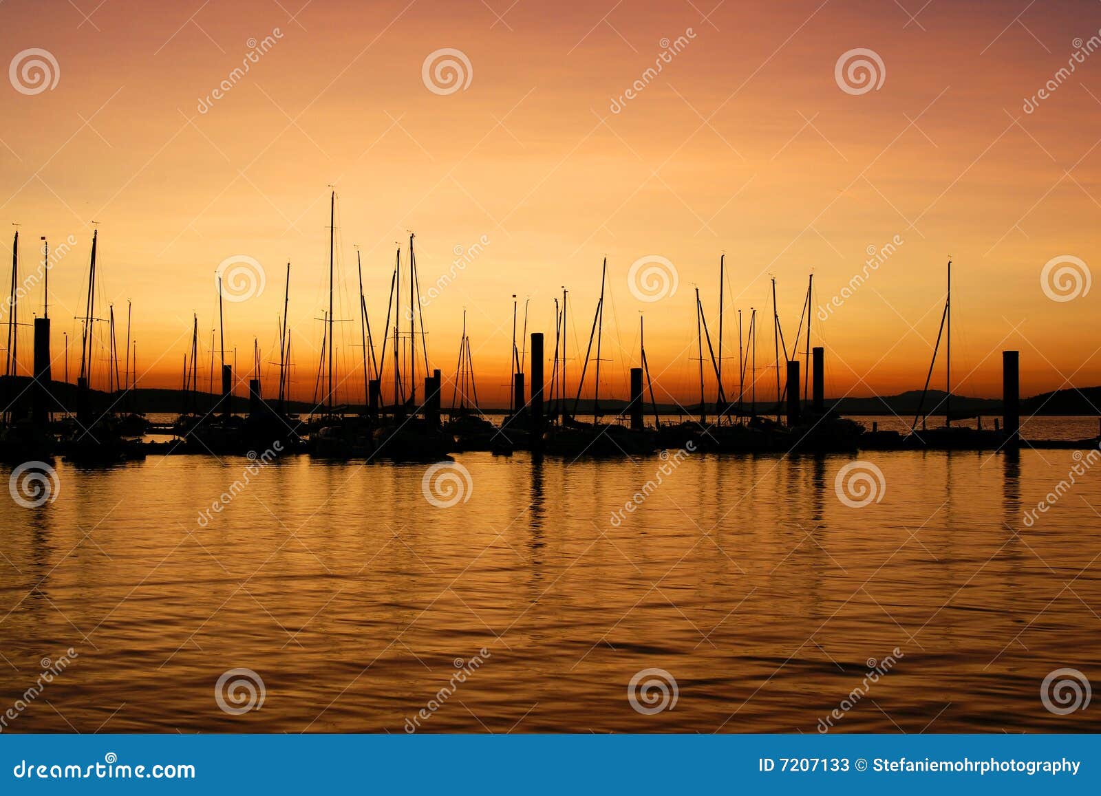 Sunrise at deserted pier with sailing boats and glowing orange sky