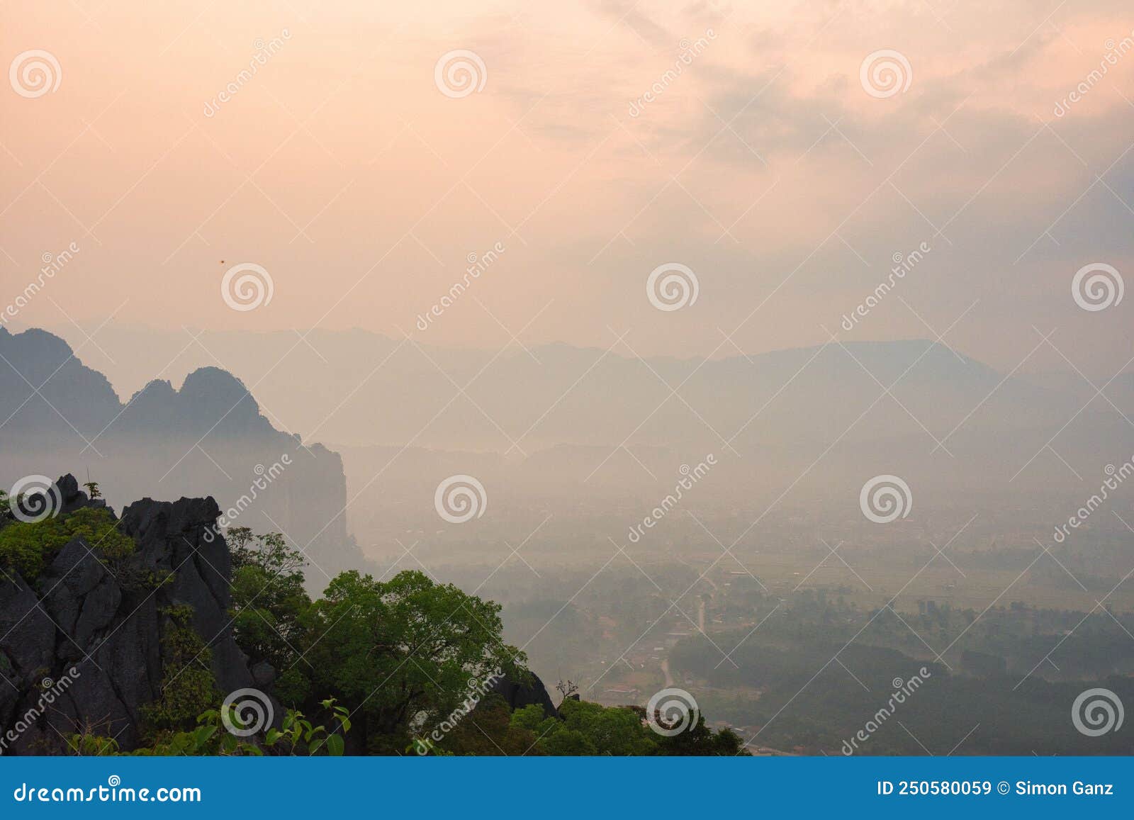 sunrise over the smoged rice fields taken from pha ngern view point near vang vieng, laos, asia