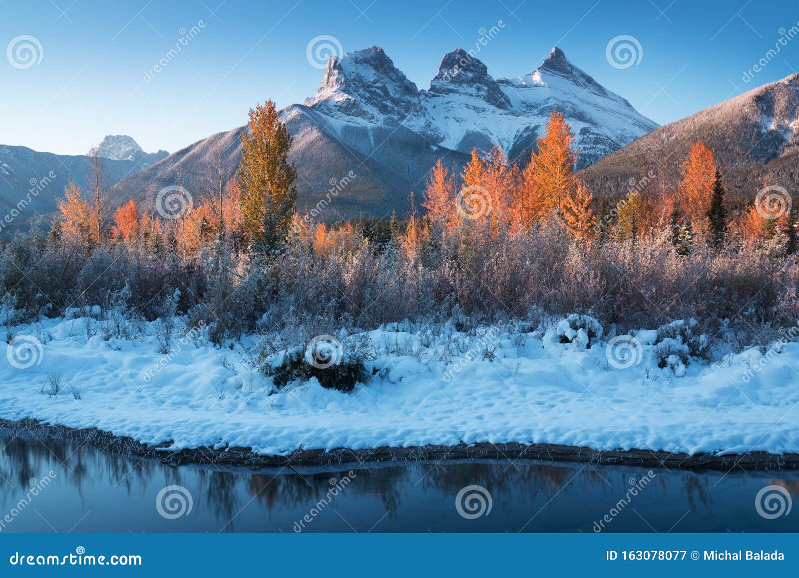 sunrise of the three sisters and the bow river from canmore near banff national park. first snow in canadian rockies.