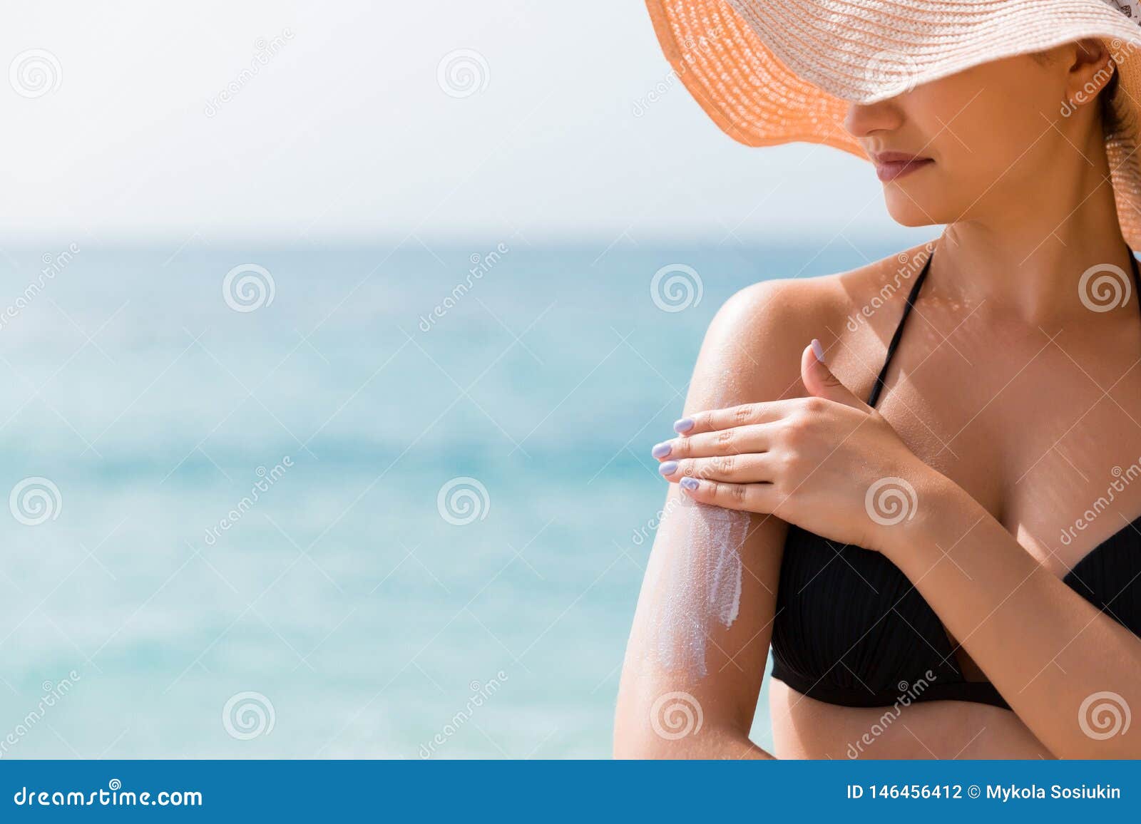 sunscreen sunblock. woman in a hat putting solar cream on shoulder outdoors under sunshine on beautiful summer day