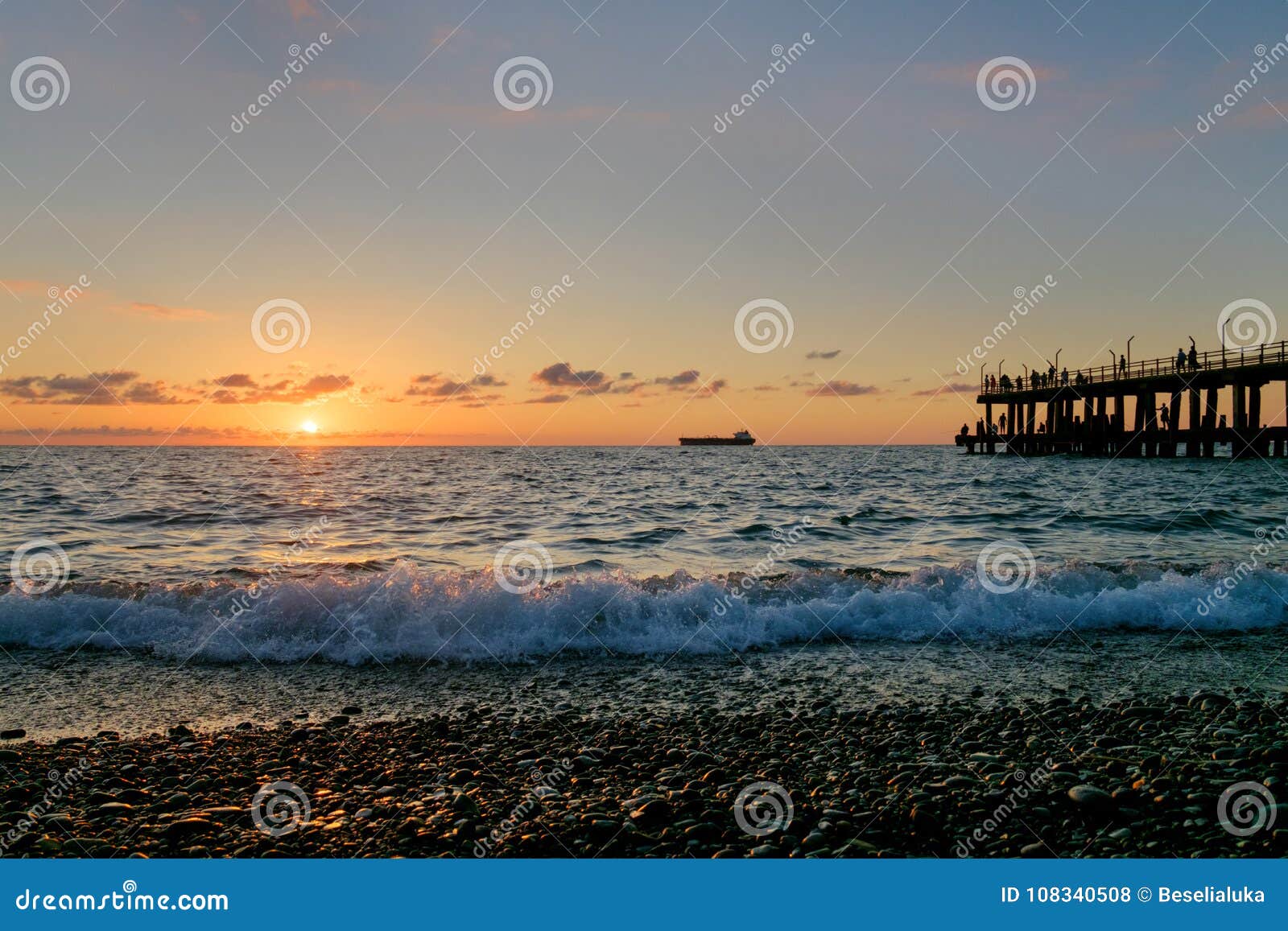 A Sunset on the Beach with Crowded Pier Stock Photo Image of people