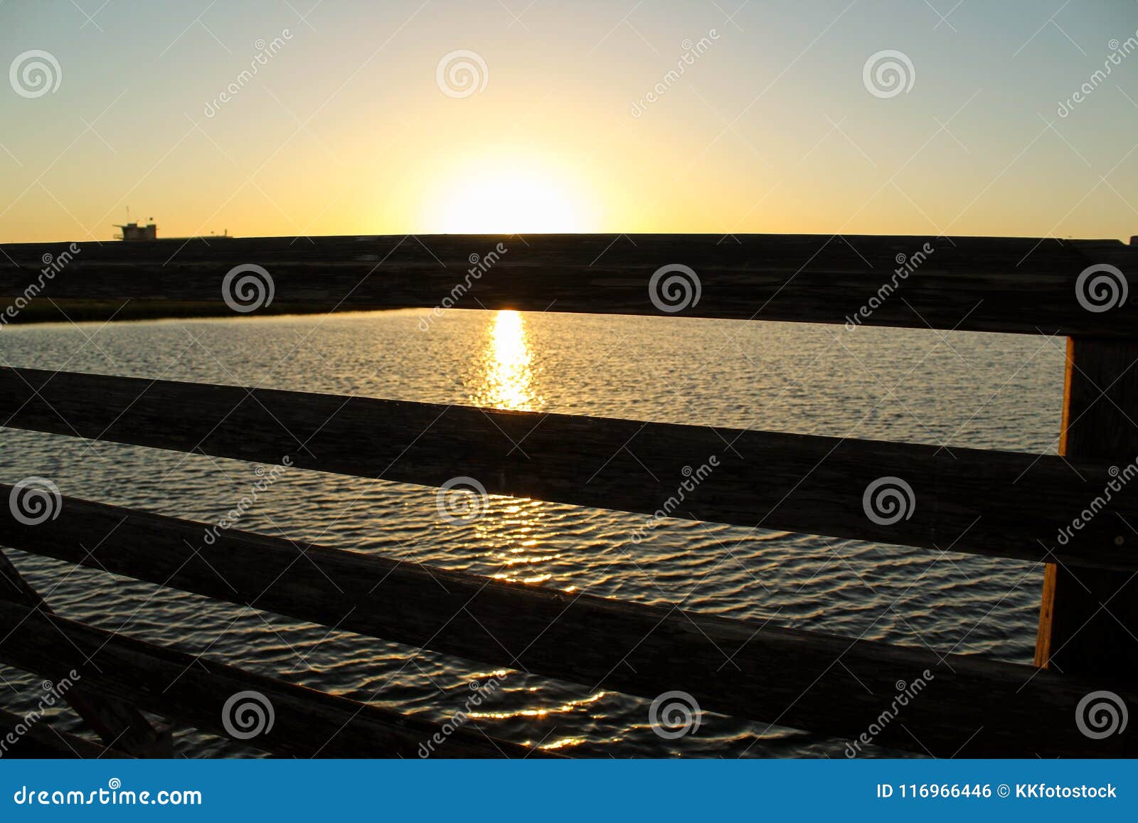 sunset at bolsa chica wetlands through a wooden bridge