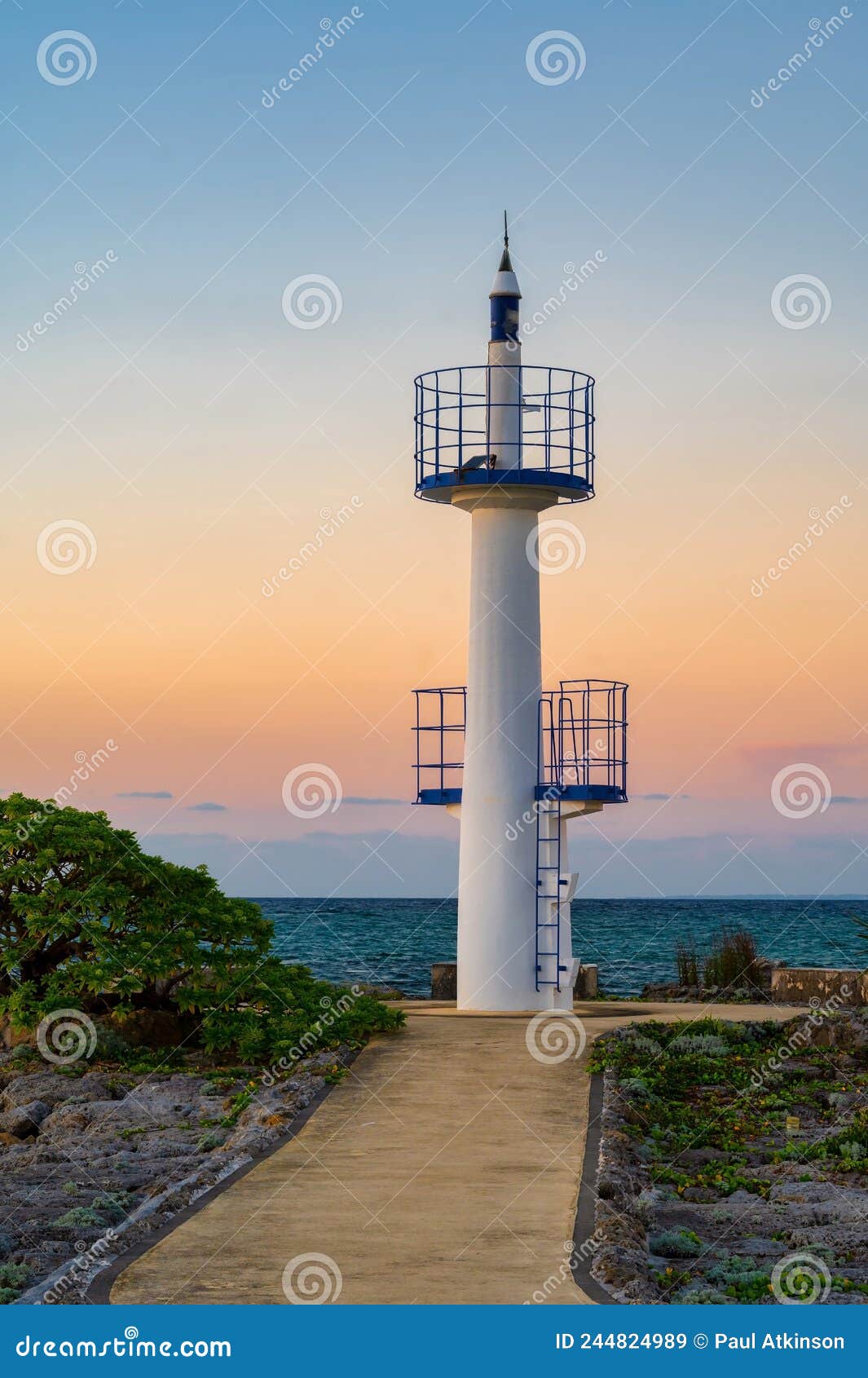 a lighthouse at sunset in onna son, okinawa, japan, with a calm sea and a glow from the setting sun