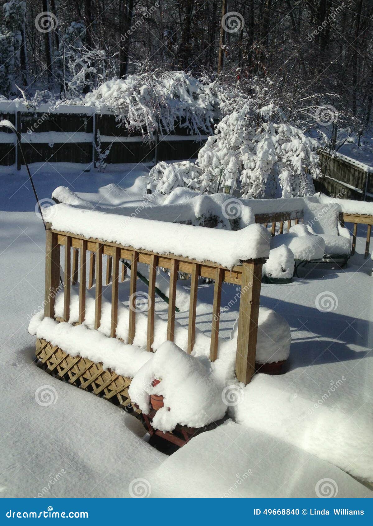 sunshine highlights snow on backyard deck and steps.