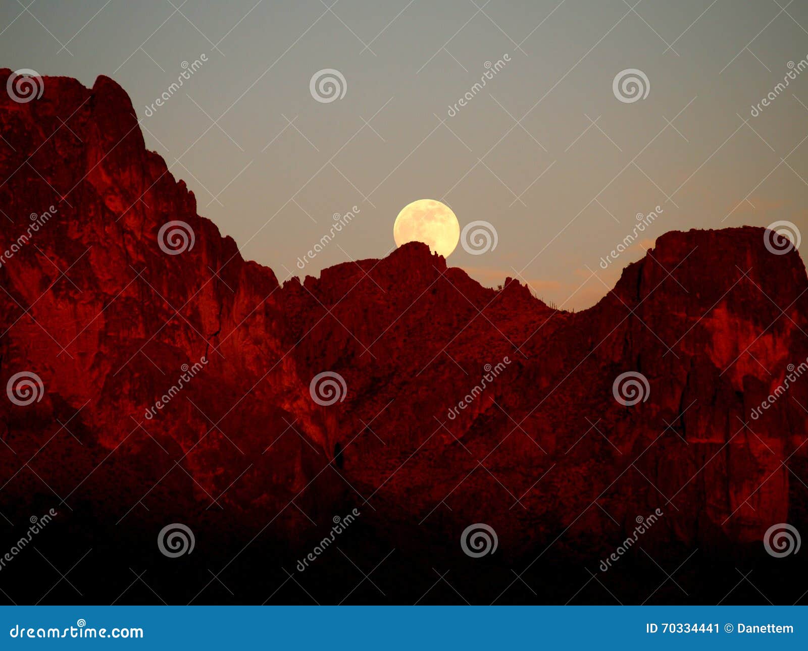 the strawberry supermoon rising over the superstition mountains at sunset