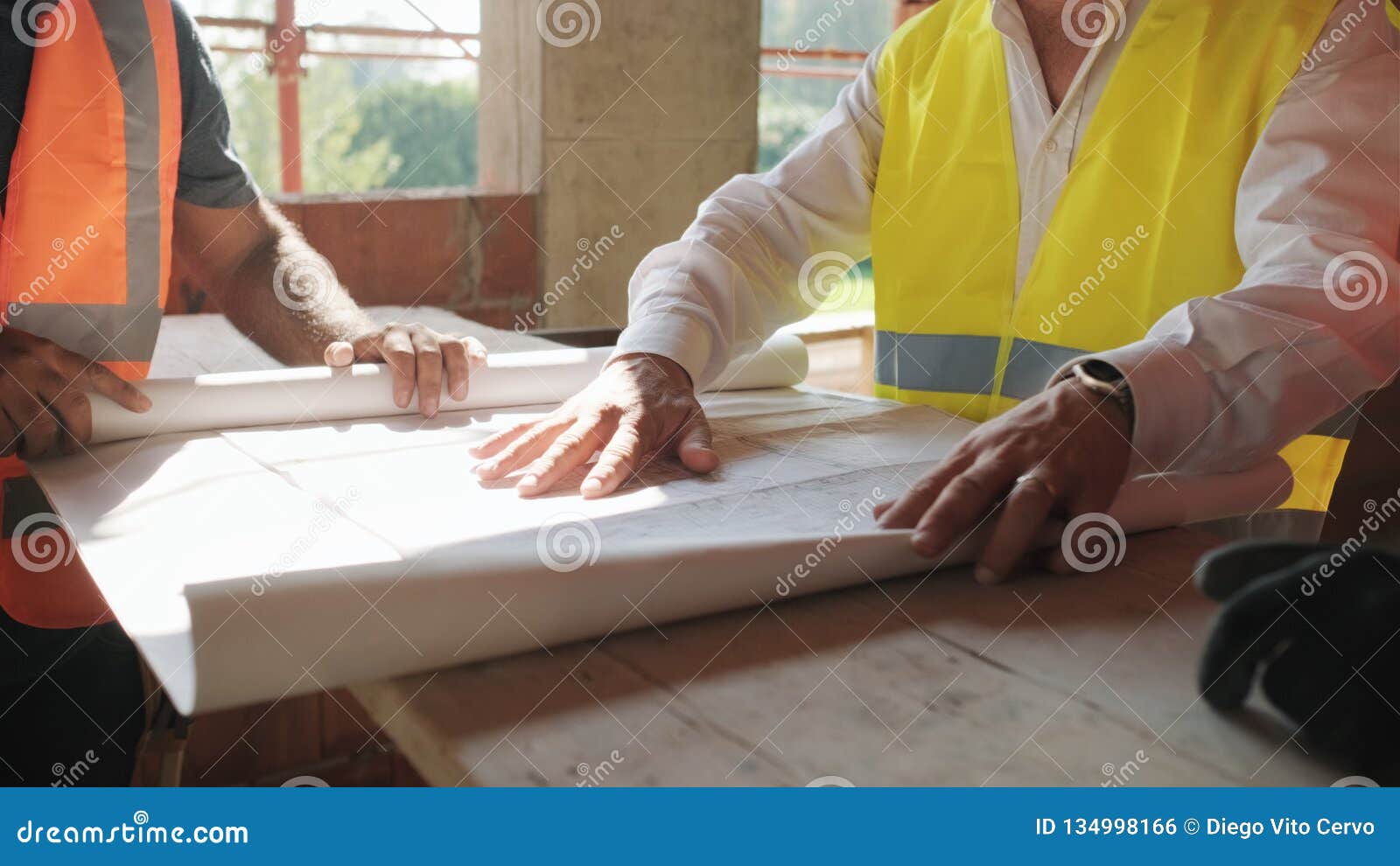 supervisor showing building plans to workers in new house