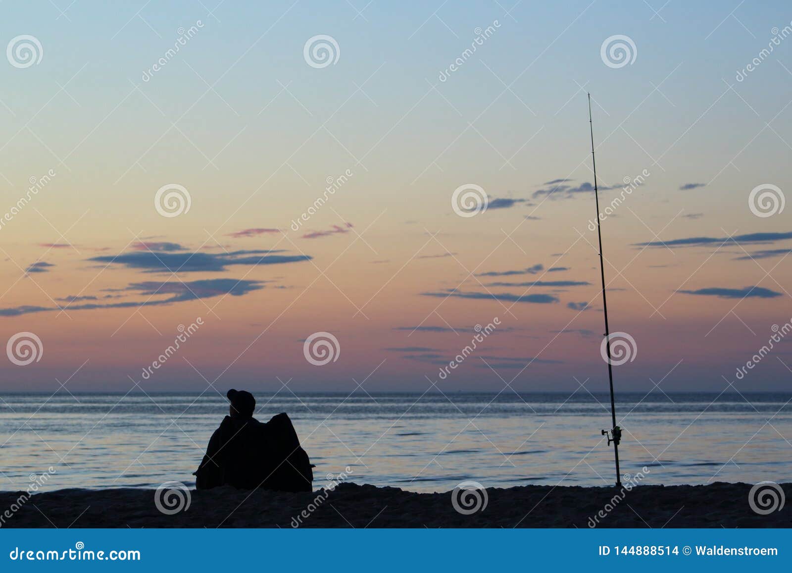 surf angler with fishing rod on the baltic sea beach at sunset