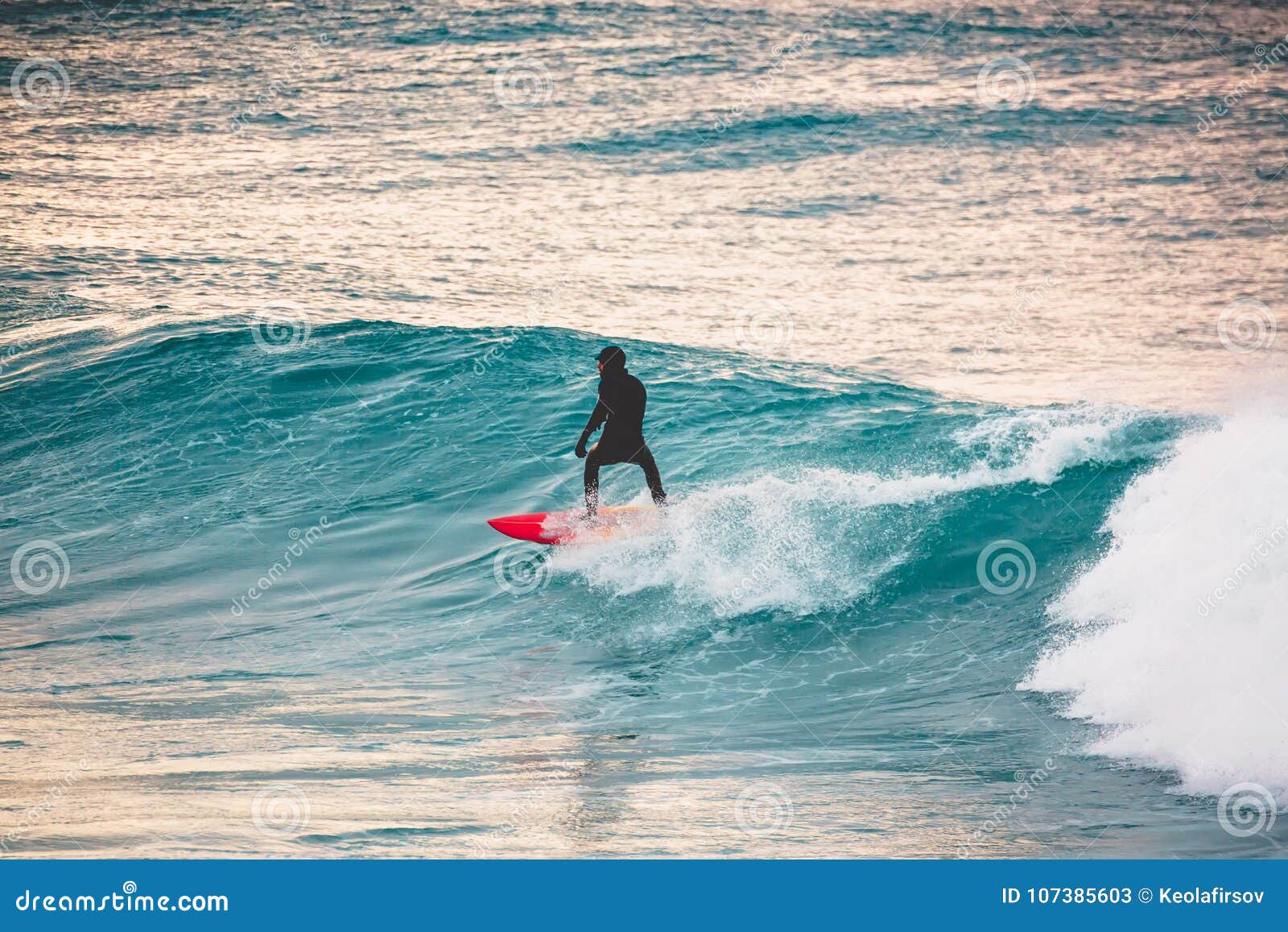 Surfer Ride on Red Surfboard on Blue Wave. Winter Surfing in Ocean