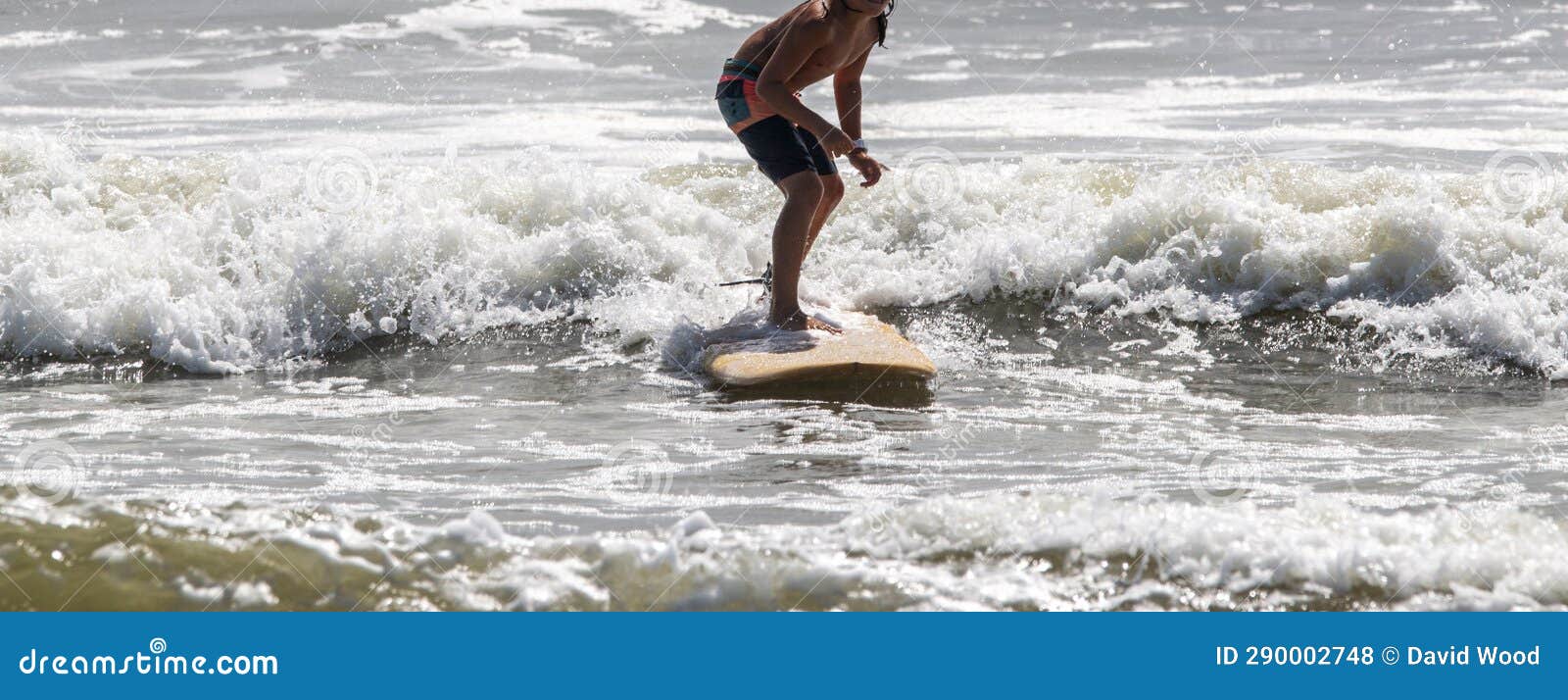 surfer rinding his surfboard close to the shore at the end of his ride