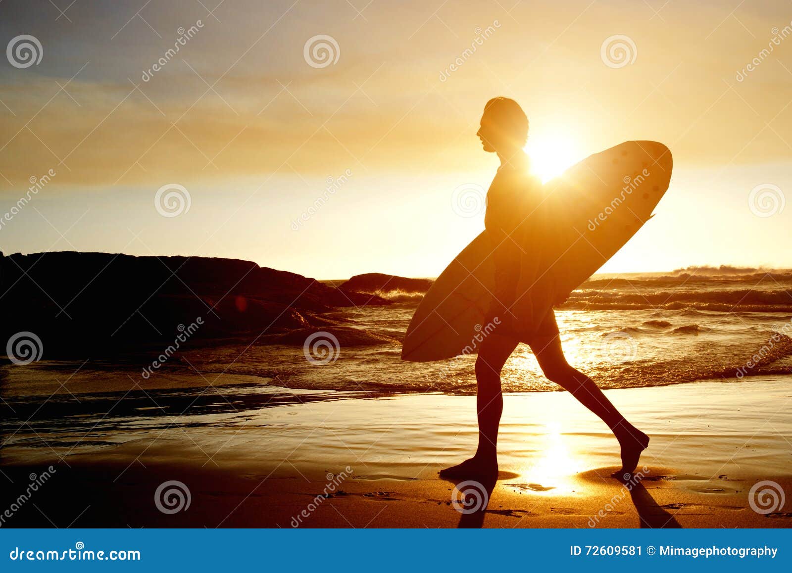 Surfer Walking on Beach with Surfboard during Sunset Stock Image