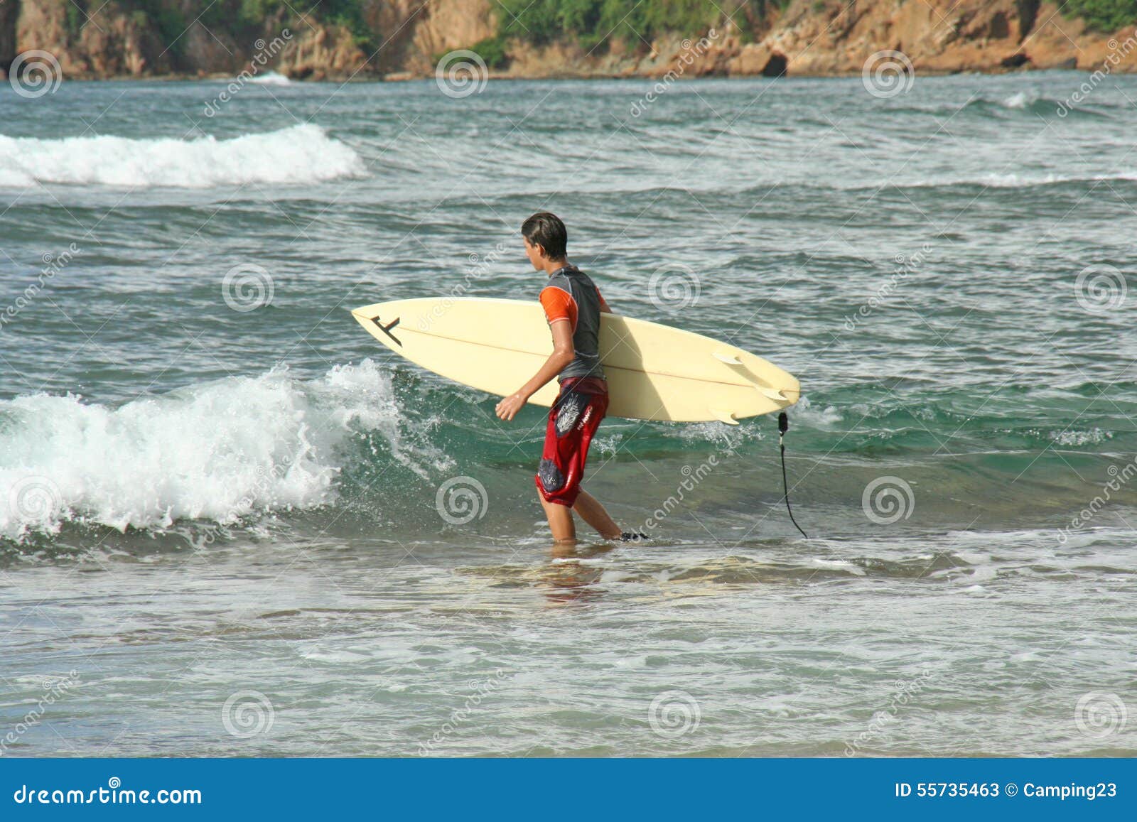 Surfer Walking with His Surfboard on a Beach. Editorial Stock Photo