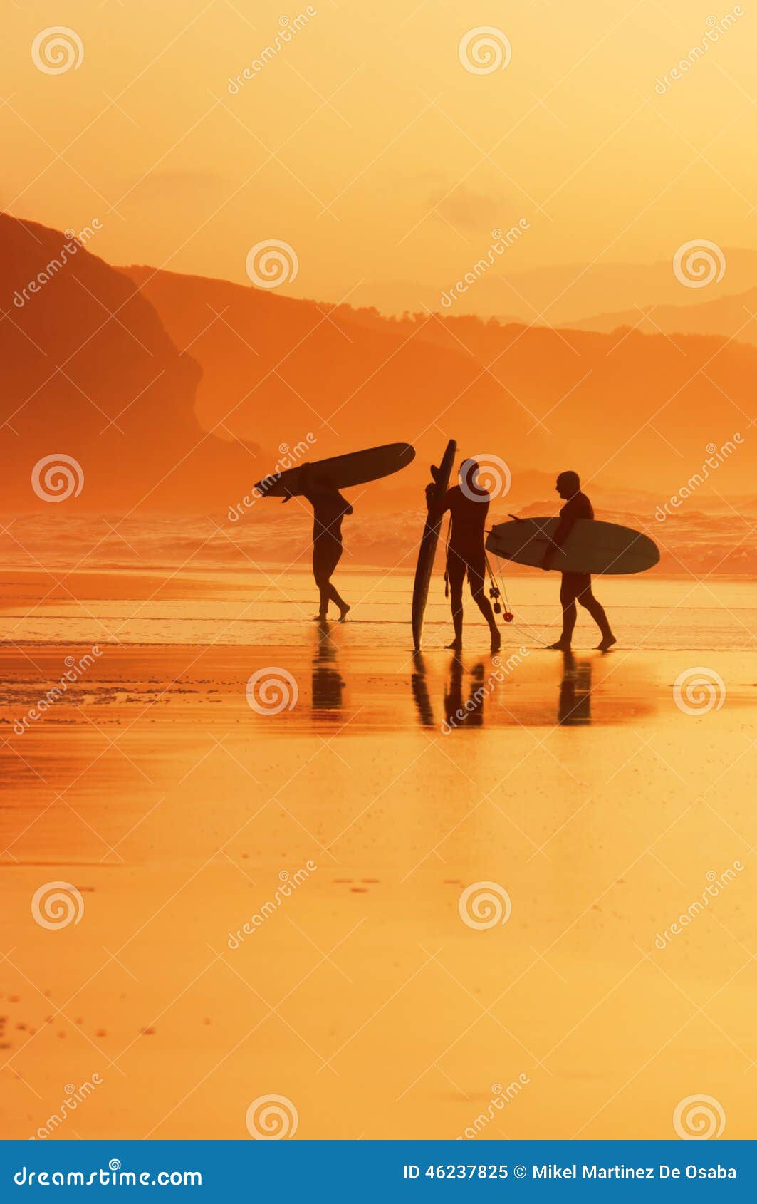 Surfisti sulla riva al tramonto. Surfisti che escono acqua sulla riva al tramonto