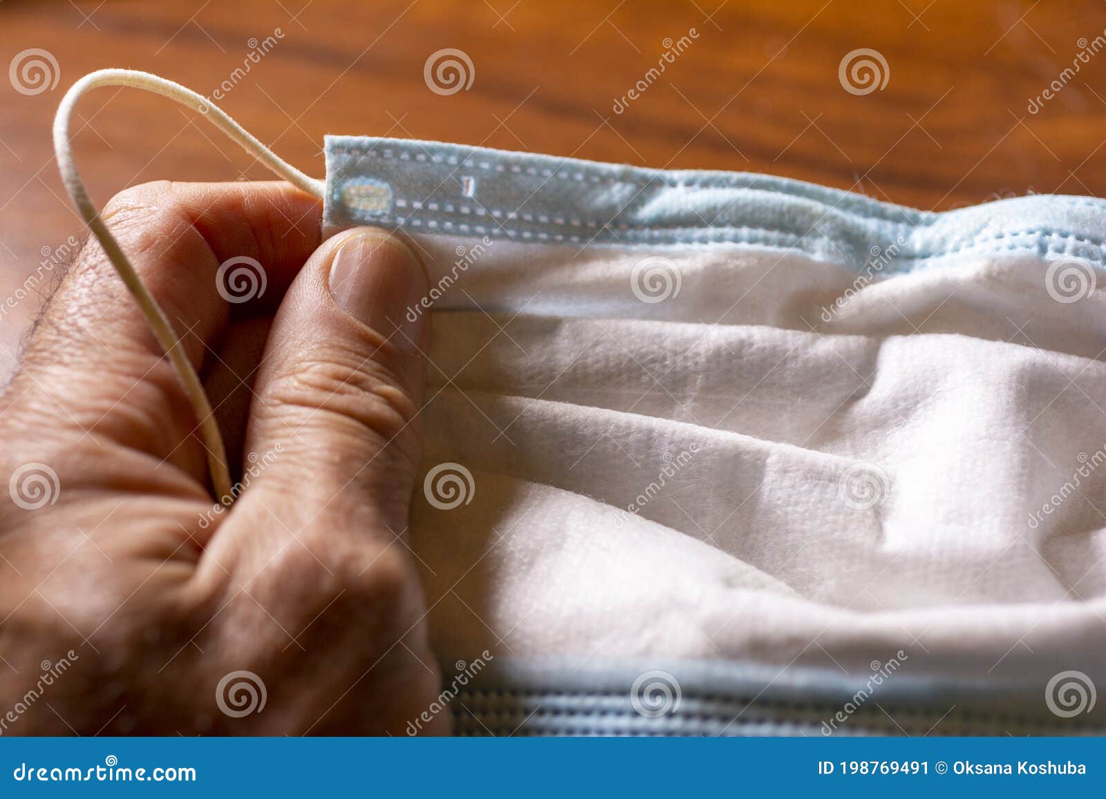 surgical anti covid mask, held in the hand by a young man