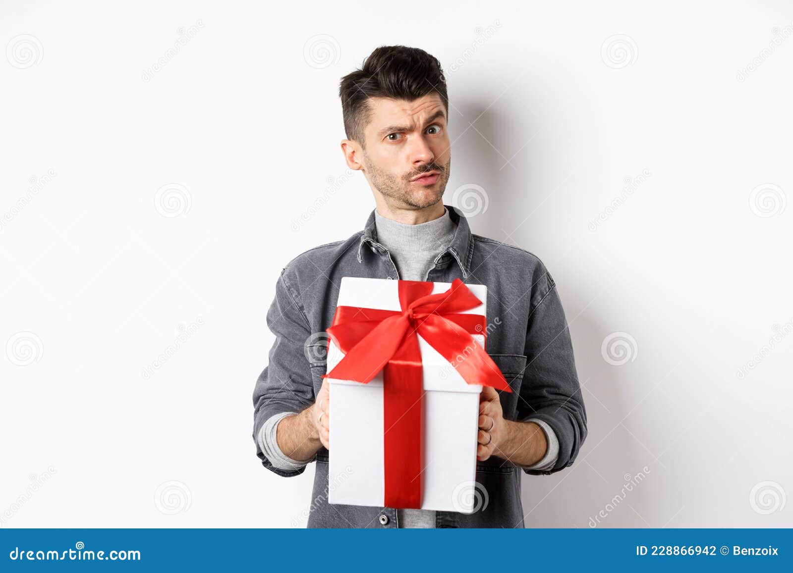 Surprenant Jeune Homme Regarder Avec Incrédulité Et Tenir Un Cadeau  Surprise Lever Le Sourcil Doutent être Suspicieux Debout Photo stock -  Image du mignon, vacances: 228866942