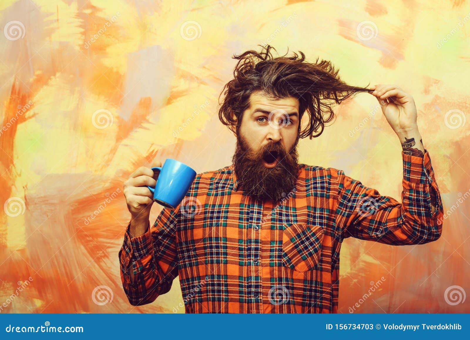 Surprised Bearded Man Pulling Stylish Fringe Hair With Blue Cup