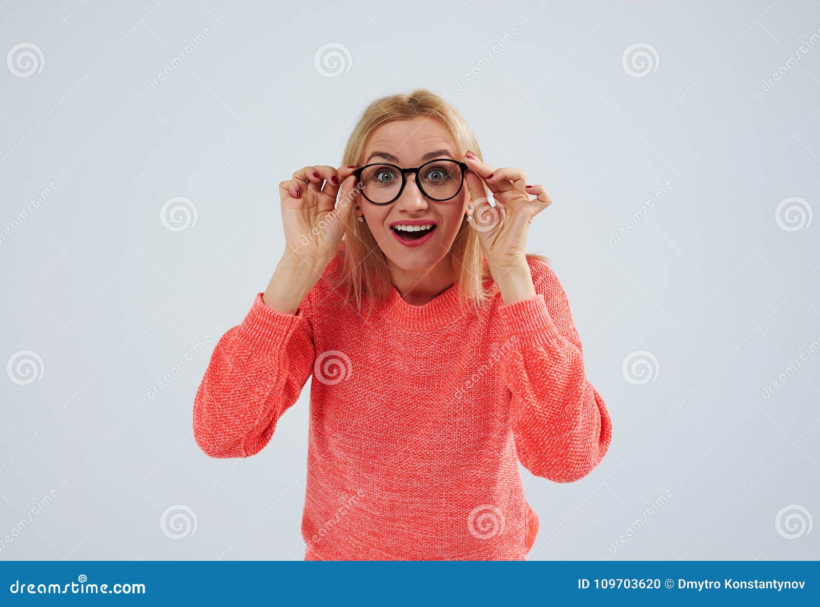 Surprised blond in sweater holding glasses. studio shot