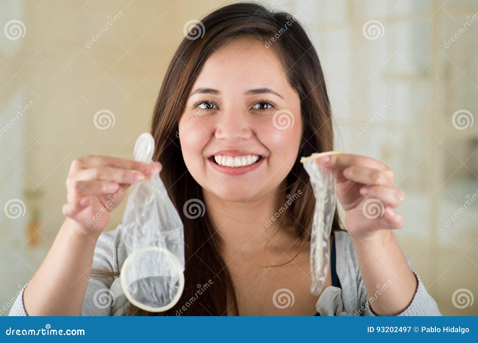 Surprised Girl Holding an Open Female Condom in One Hand and an Open Male Condon in Her Other Hand, Safe Sex Concept Stock Image photo