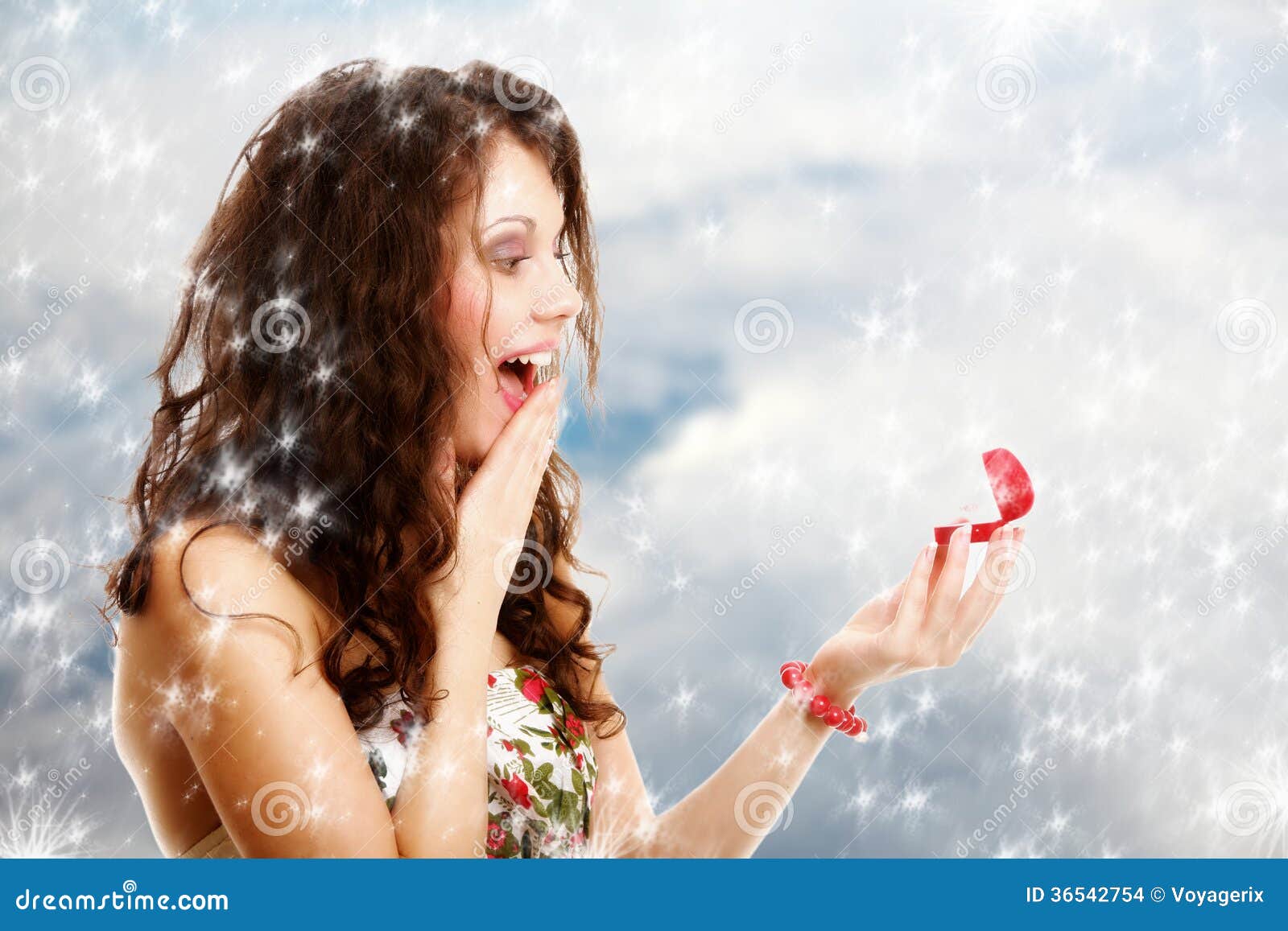 Surprised girl opening red gift box with engagement ring. Winter. Surprised shocked happy girl young woman opening present red heart shaped gift box with engagement ring. Valentines day. Winter snow background.