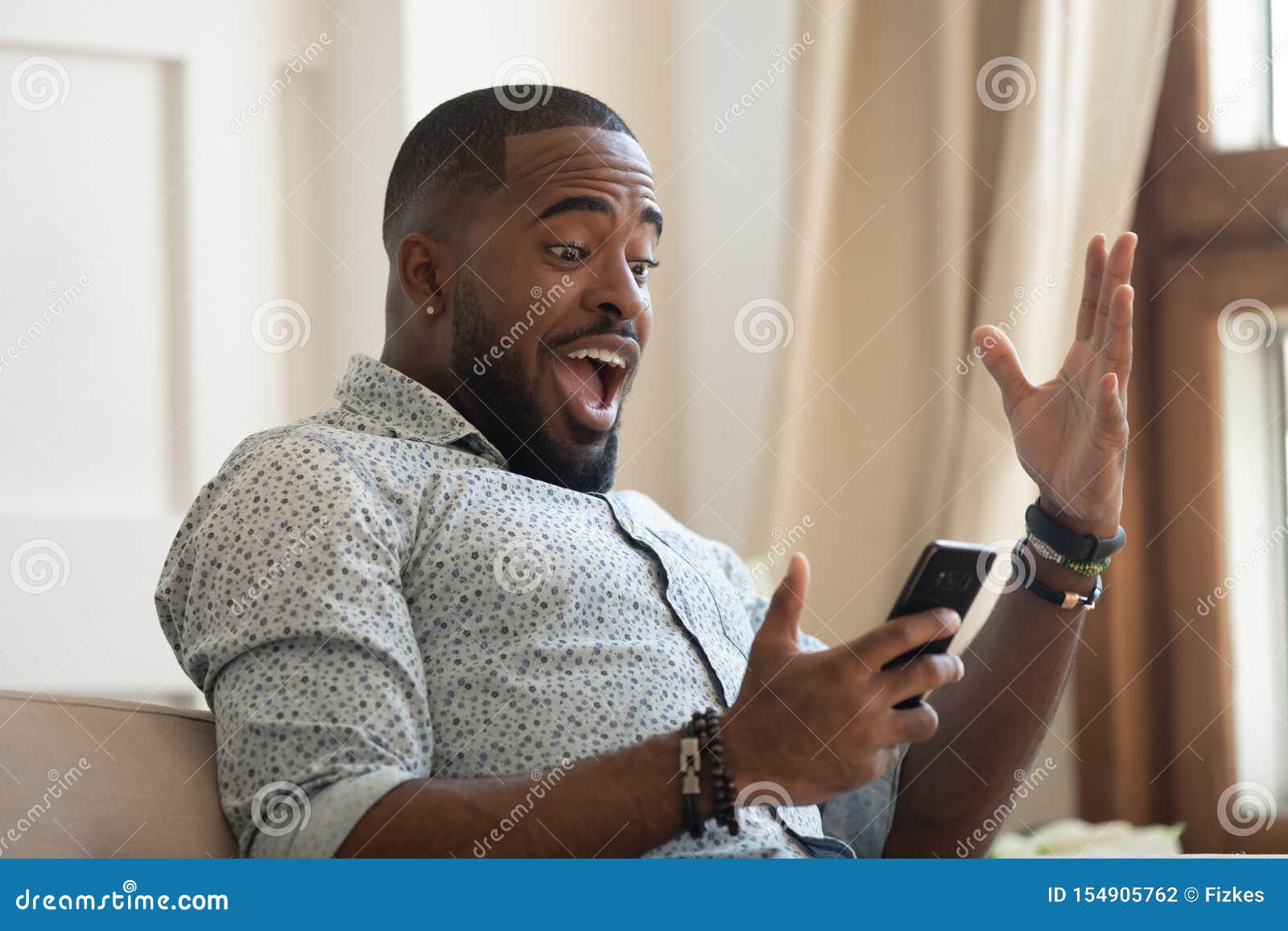 surprised happy african man looking at cellphone read good news