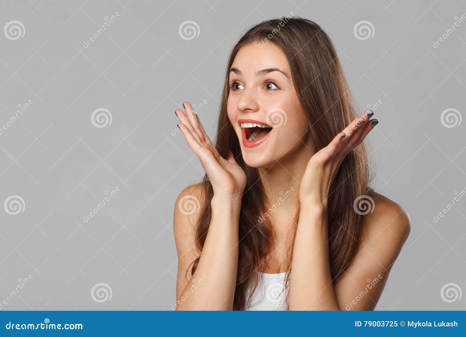 surprised happy beautiful woman looking sideways in excitement.  on gray background