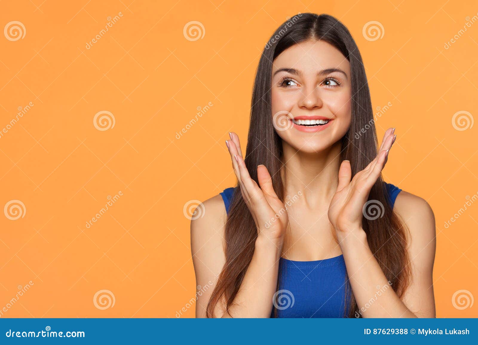 surprised happy beautiful woman looking sideways in excitement,  on orange background