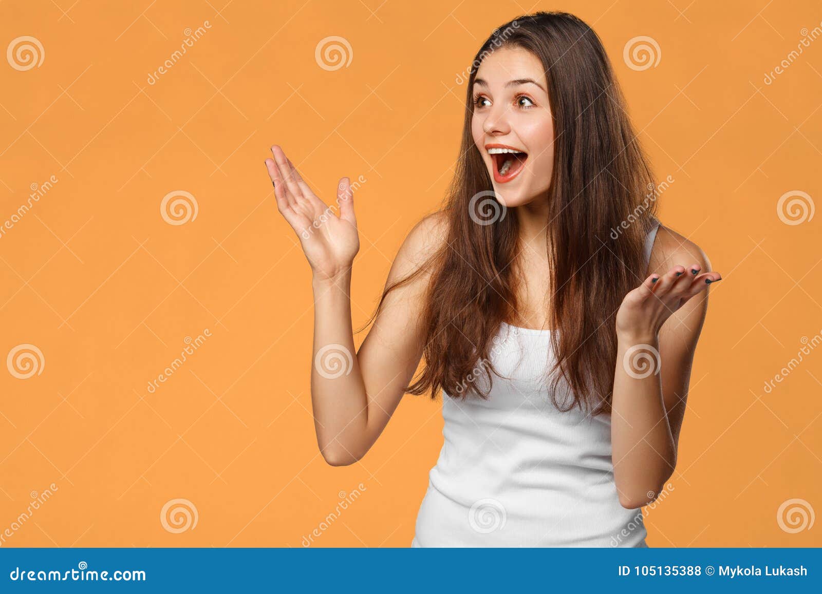 surprised happy beautiful woman looking sideways in excitement,  on orange background