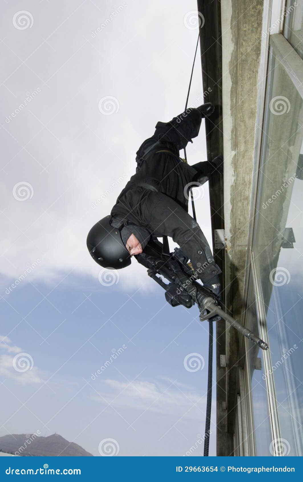 SWAT Team Officer Aiming Assault Rifle while Rappelling Stock Photo