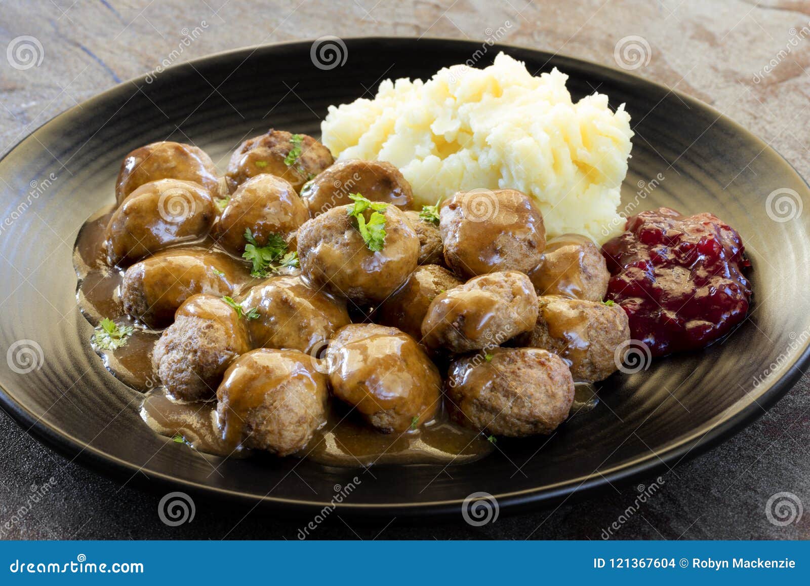swedish meatballs with lingonberry on black plate over slate