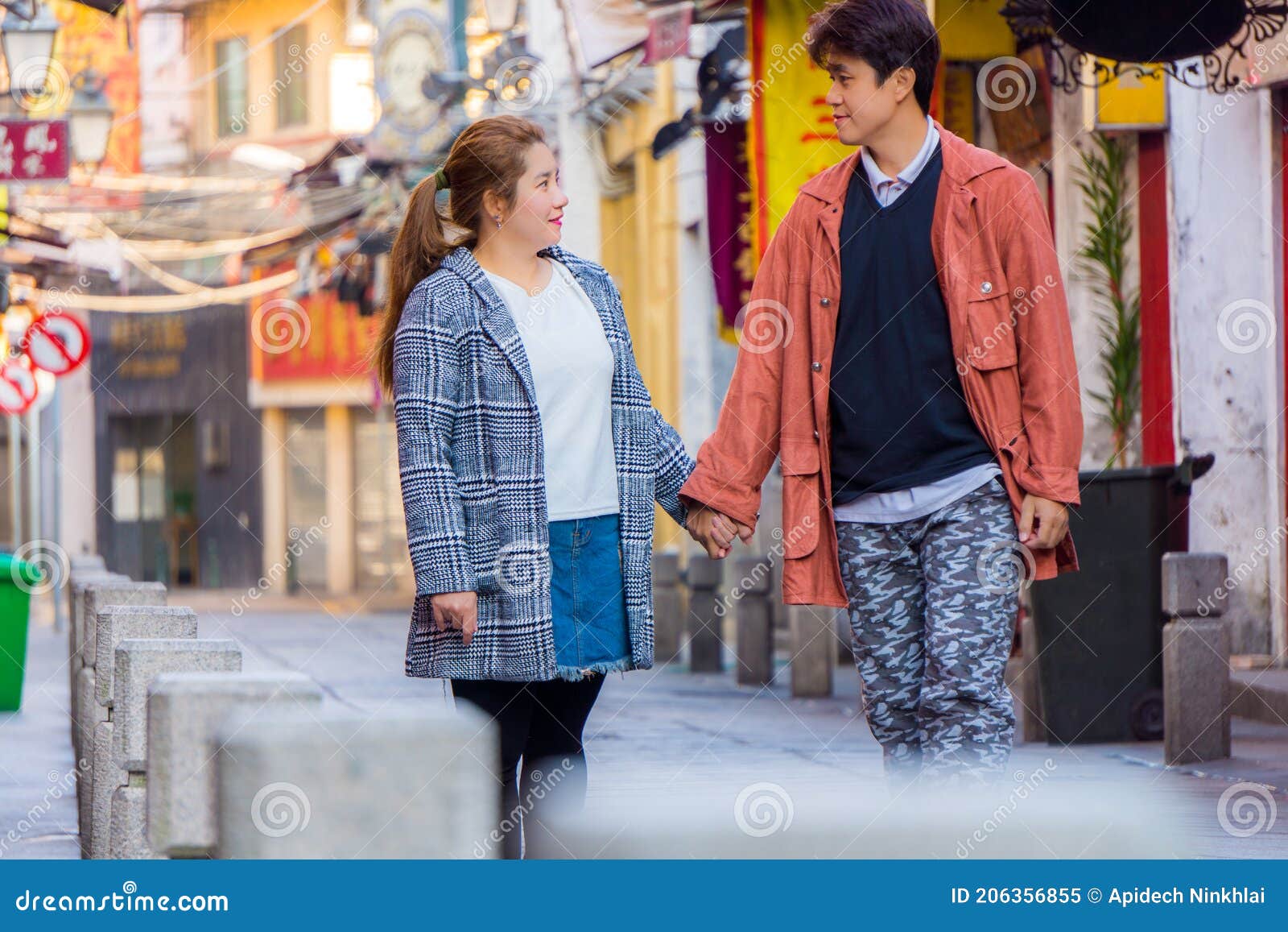 sweet asian couple holding hands and staring into eyes each other on happiness street.