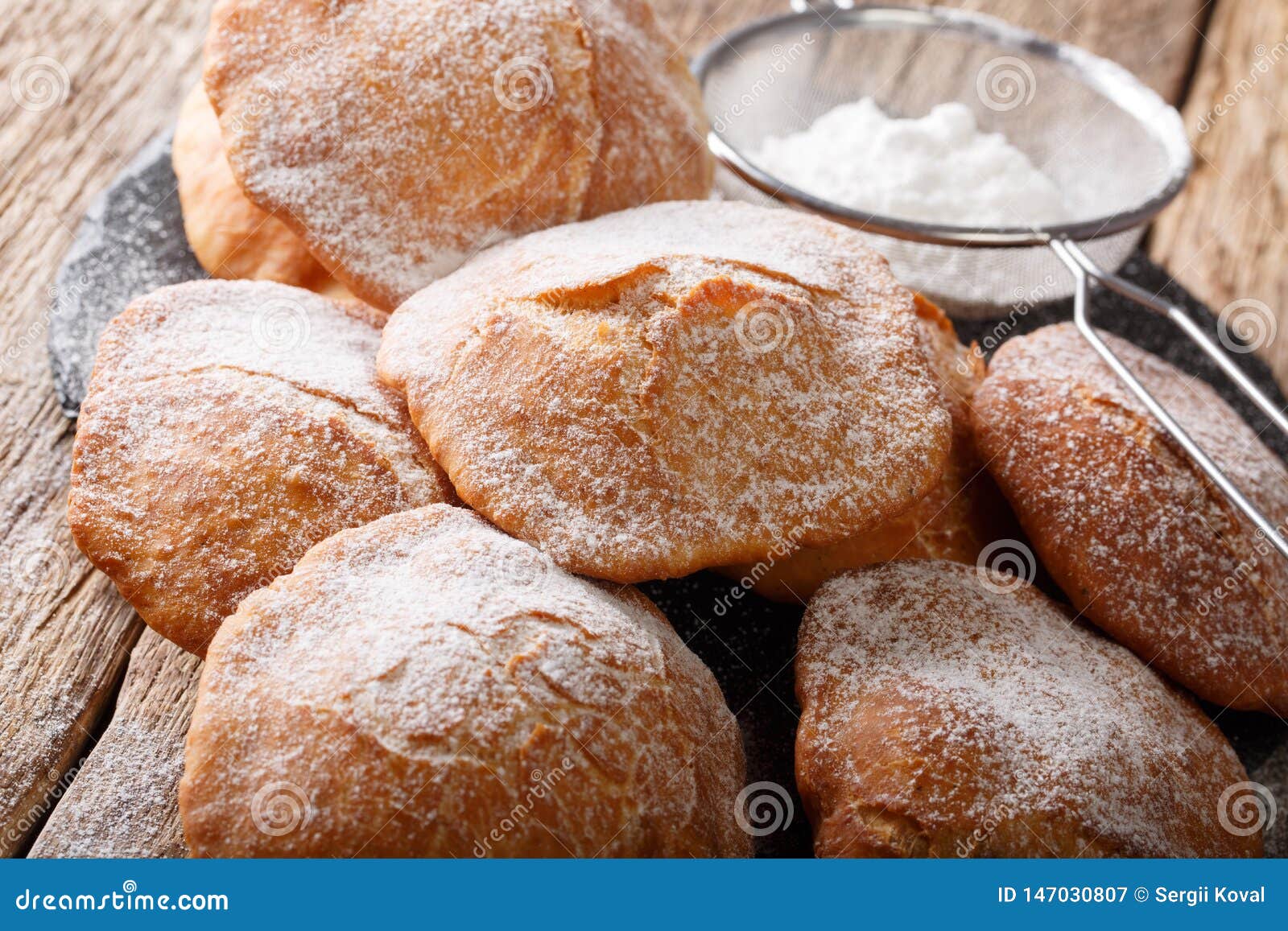 sweet deep-fried bunuelos sprinkled with powdered sugar close-up. horizontal