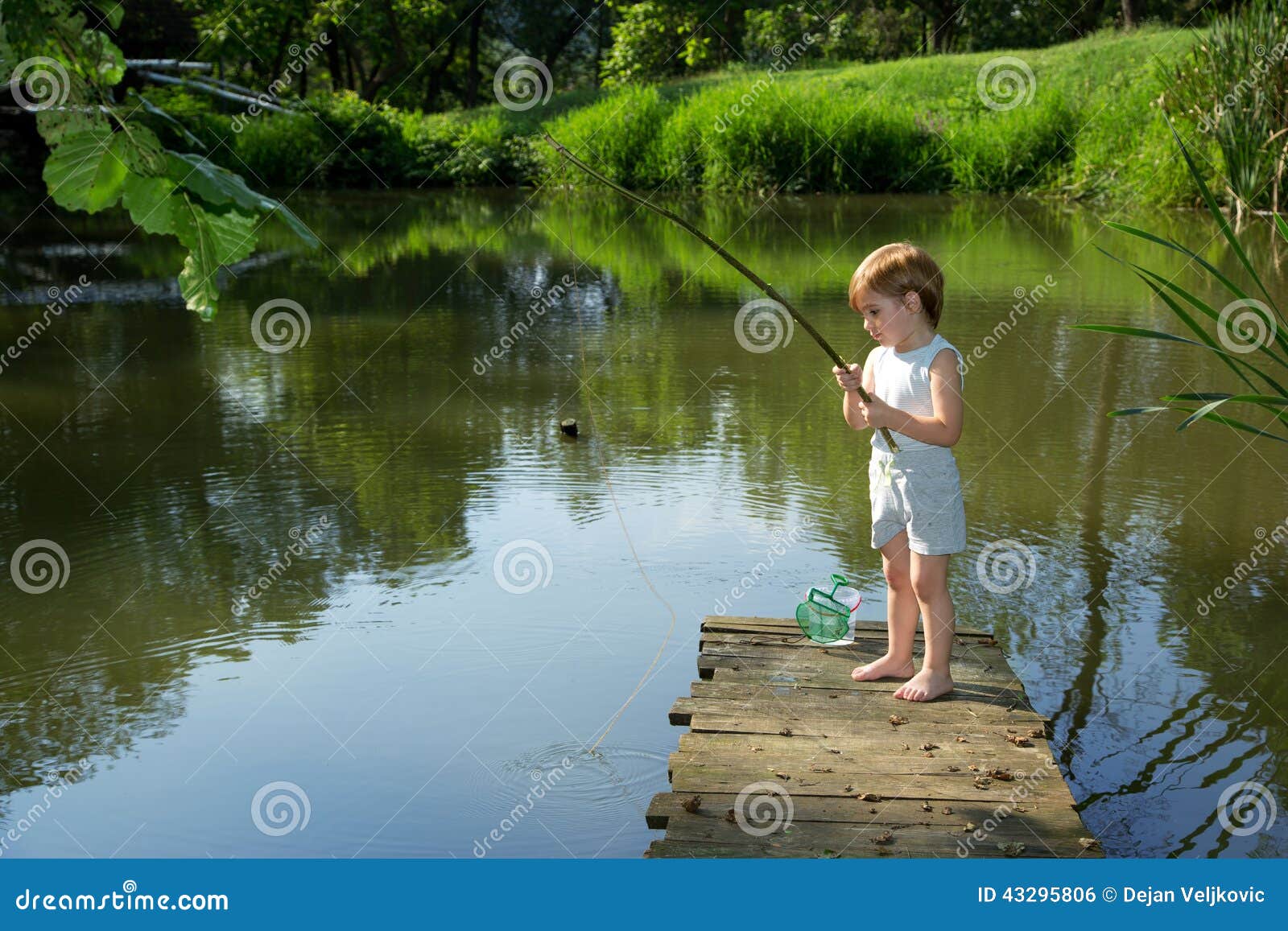 Boy fishing on lake shore - Stock Photo - Dissolve