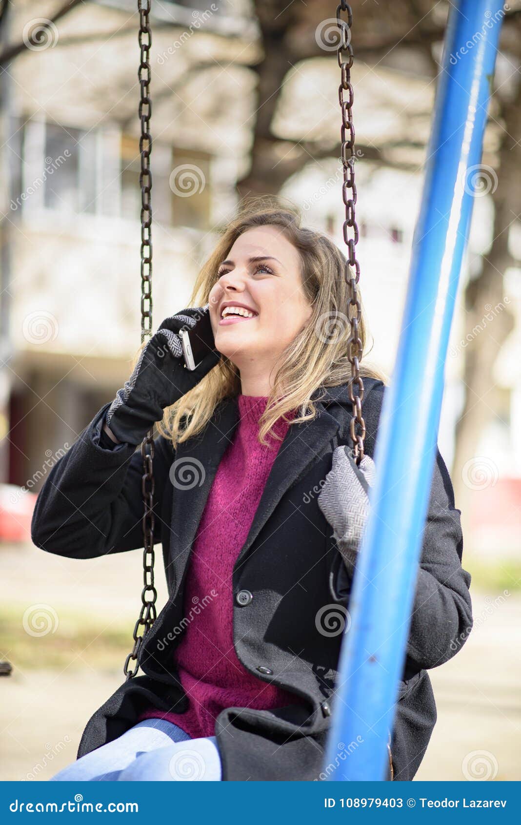 Sweet Young Woman Having a Lovely Conversation while Swinging in a Park Stock Image