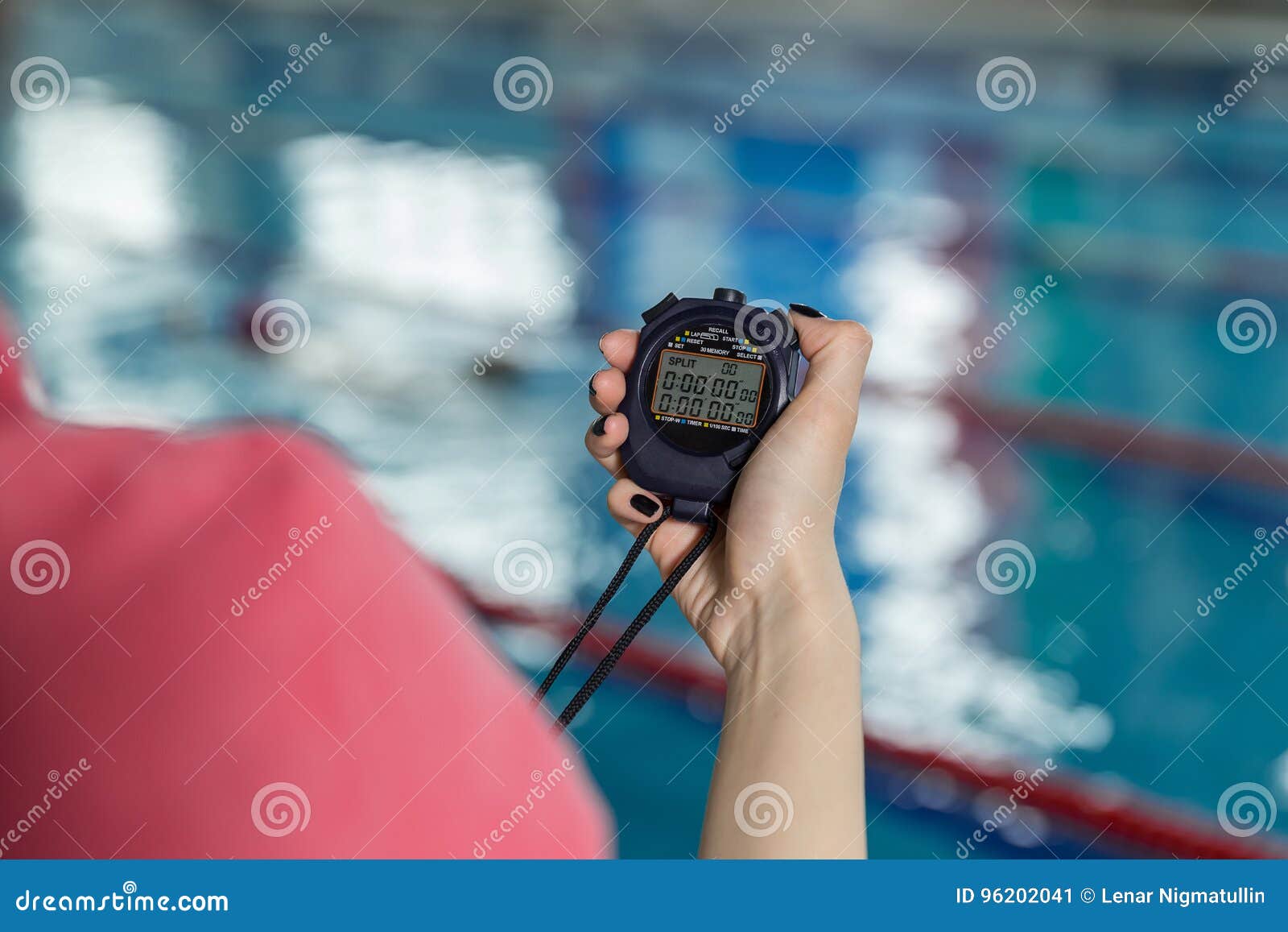 Swimming Coach Holding Stopwatch Poolside At The Leisure Center. Stock