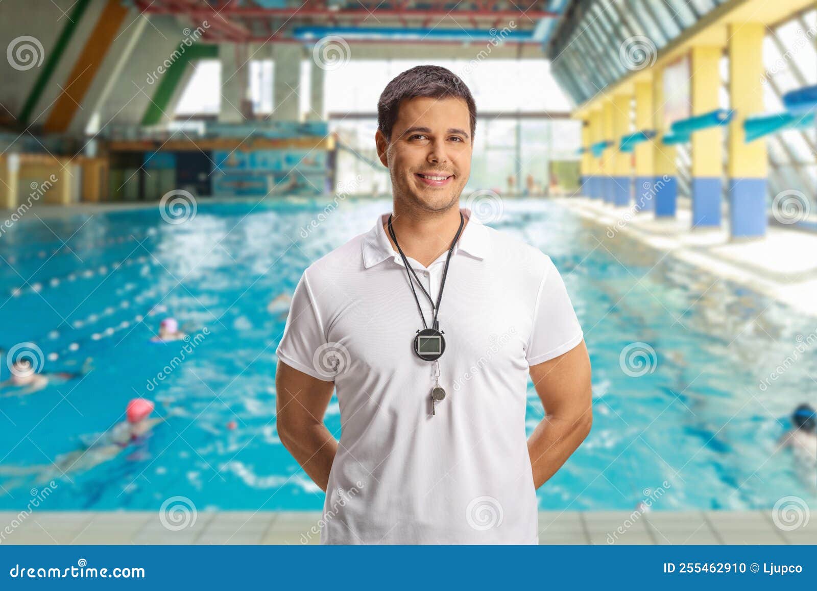 Swimming Coach with a Wistle and Stopwatch Posing in an Indoor Swimming