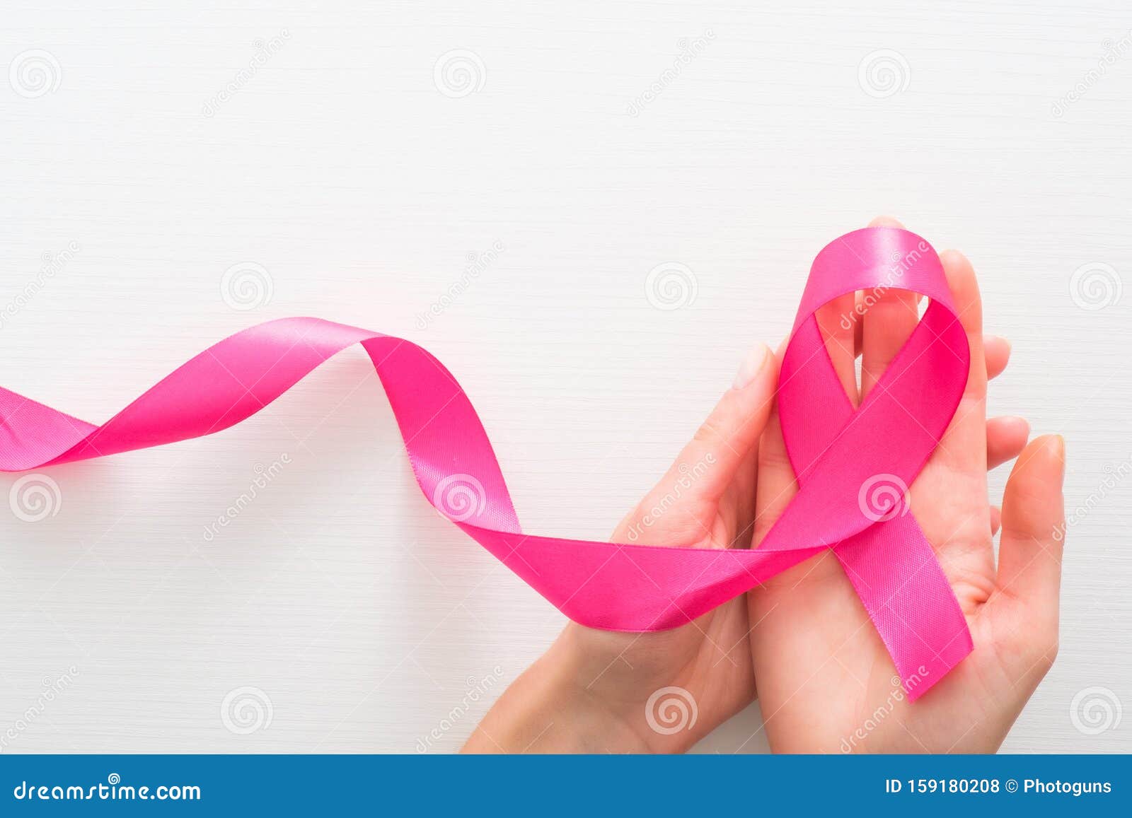  of breast cancer awareness month in october. female hands holding pink breast cancer awareness ribbon over white background