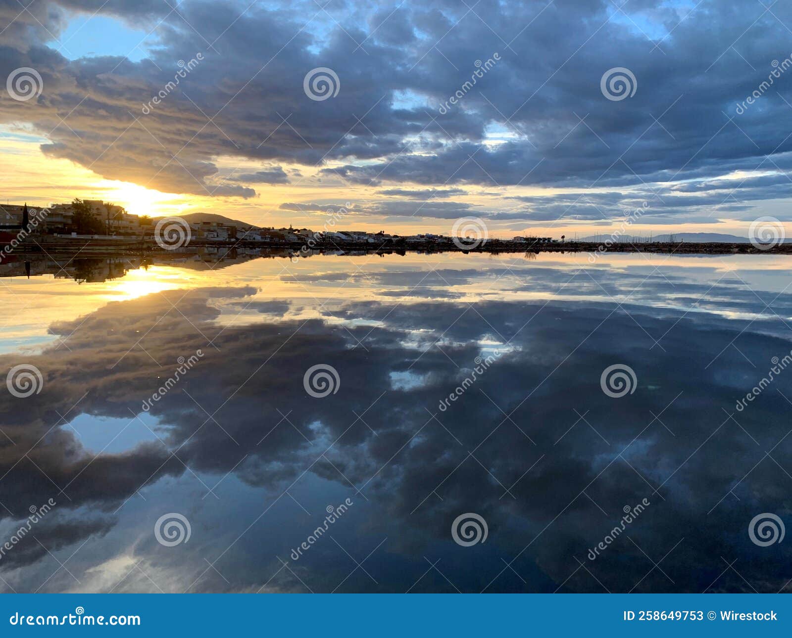 symmetric view of the fluffy clouds reflecting on the lake water at sunset in los nietos