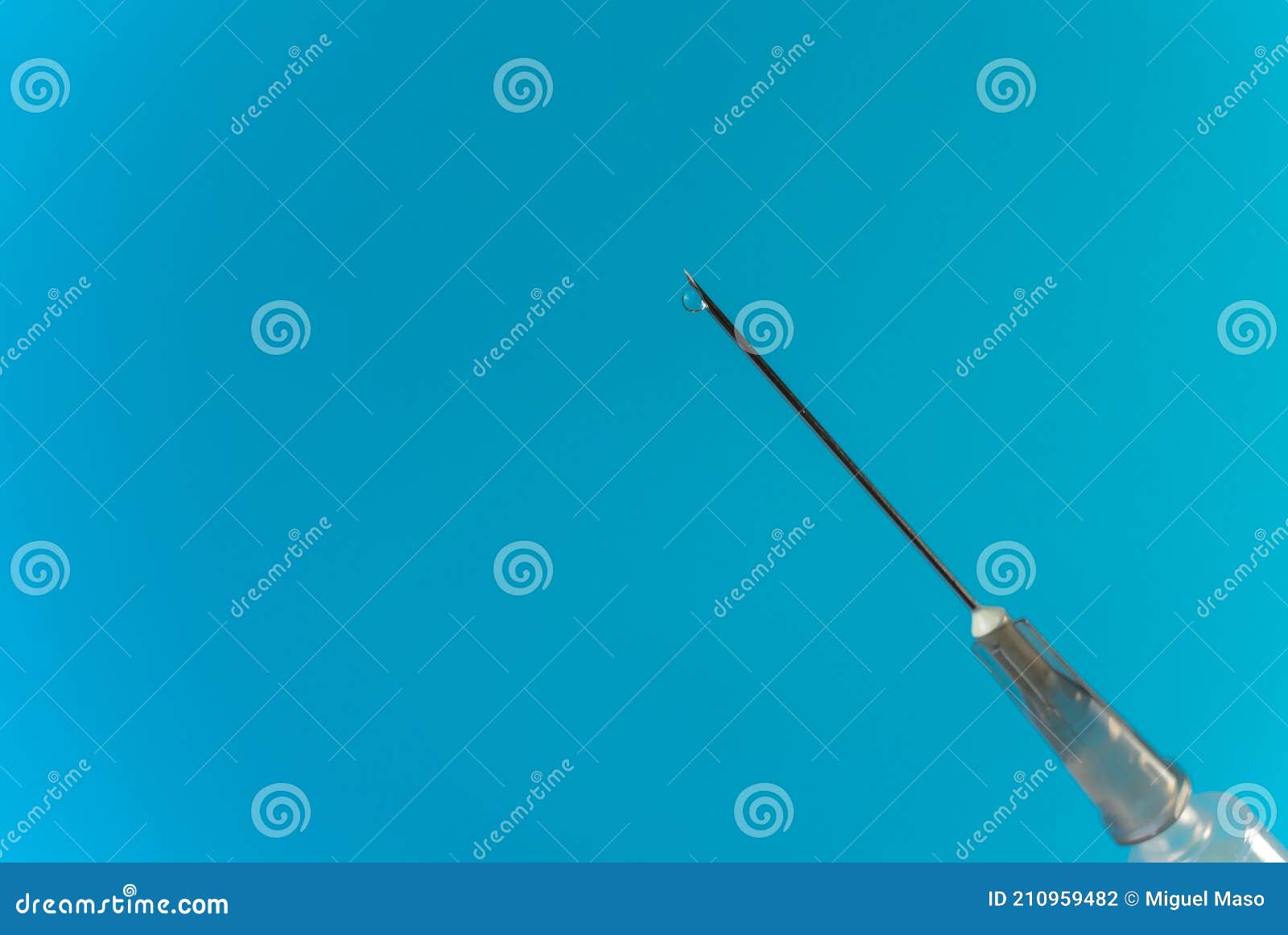 A Syringe in the Foreground Appears from the Lower Right Corner of the