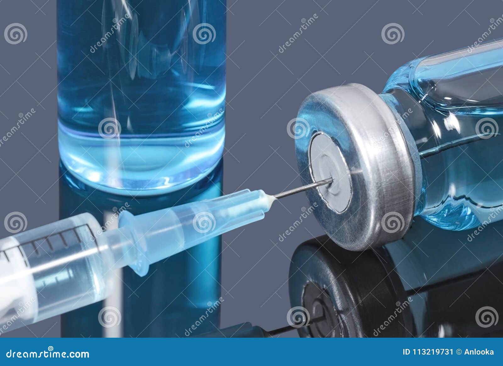 syringe with a needle stuck in a vial of blue vaccine on dark background