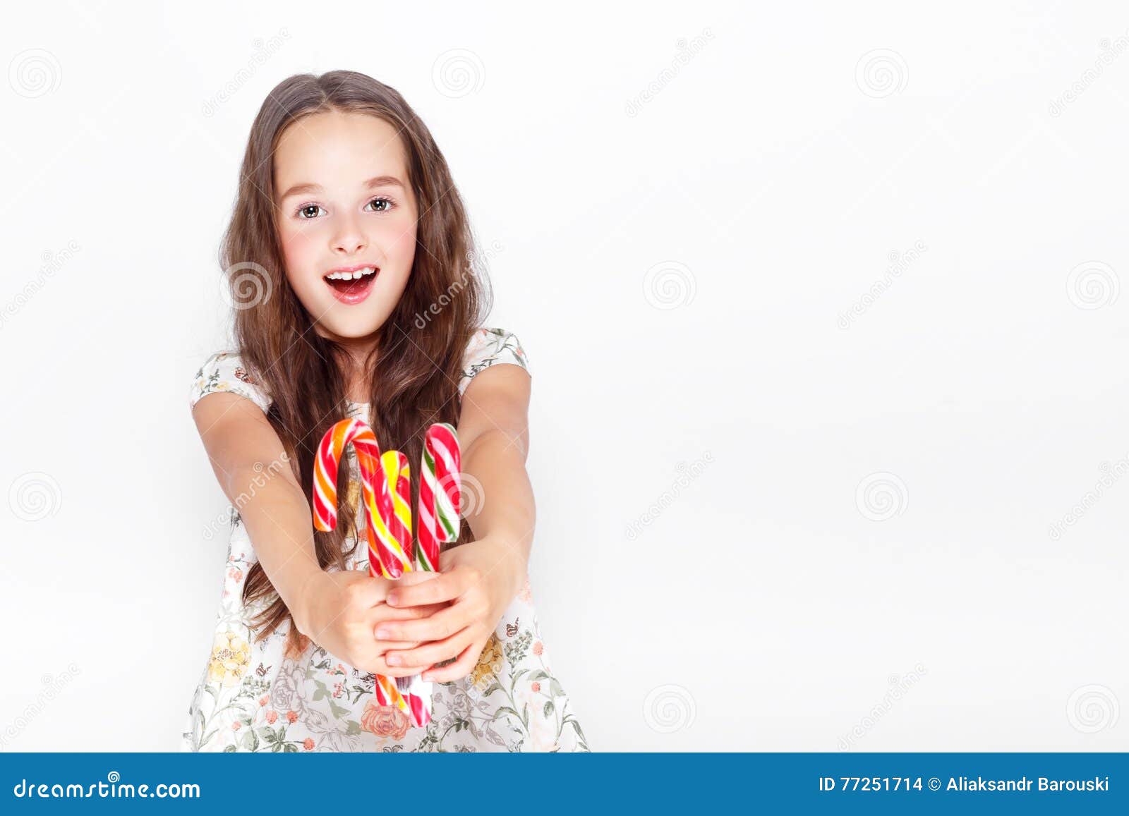 Szczęśliwa, uśmiechnięta śliczna małej dziewczynki łasowania cristmas cukierku trzcina, Pozować przeciw białej ścianie