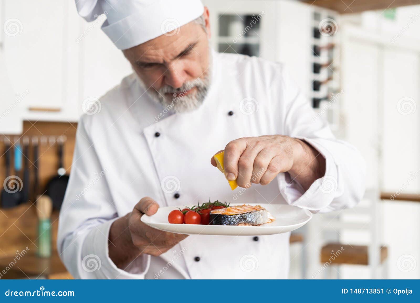 Szef kuchni z pilno?ci apretury naczyniem na talerzu, ryba z warzywami. Chef with diligence finishing dish on plate, salmon with vegetables