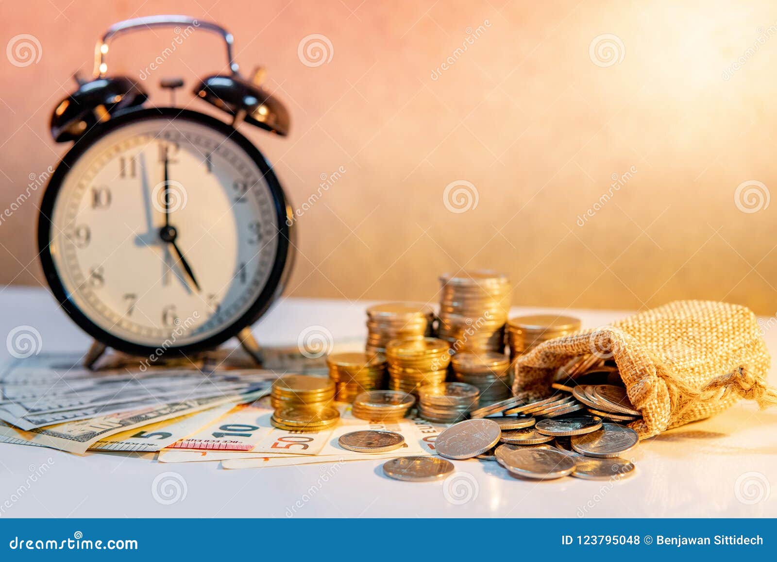 clock and coin stack on table. time investment