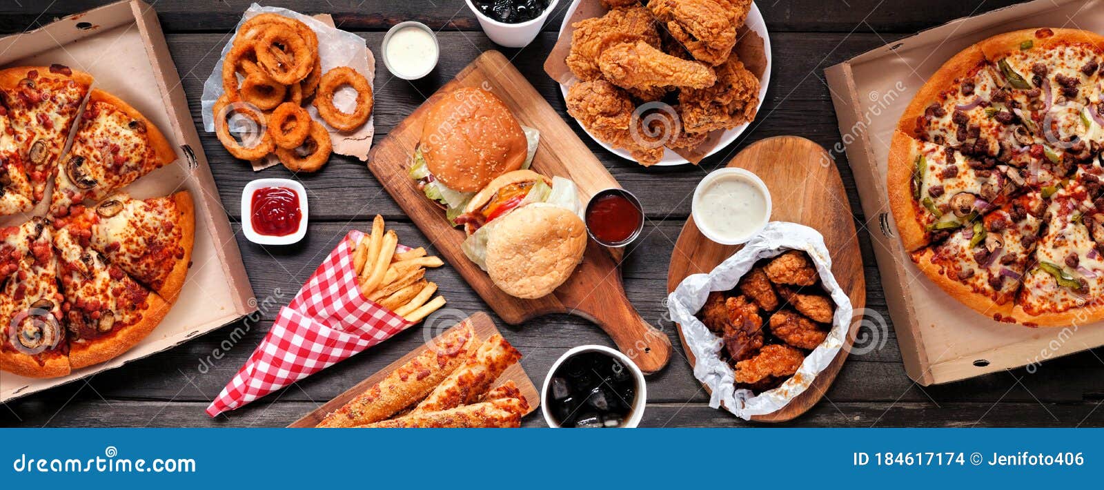 table scene of assorted take out or delivery foods, top down view on a dark wood banner