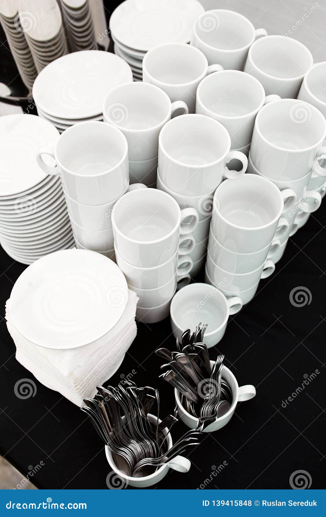 A Table Set of White Mugs, Plates and Spoons on a Buffet Stock Photo
