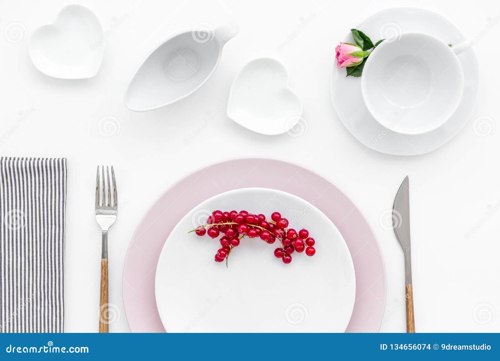 table setting with plates, wineberry, fork, knife and flower on white kitchen background top view