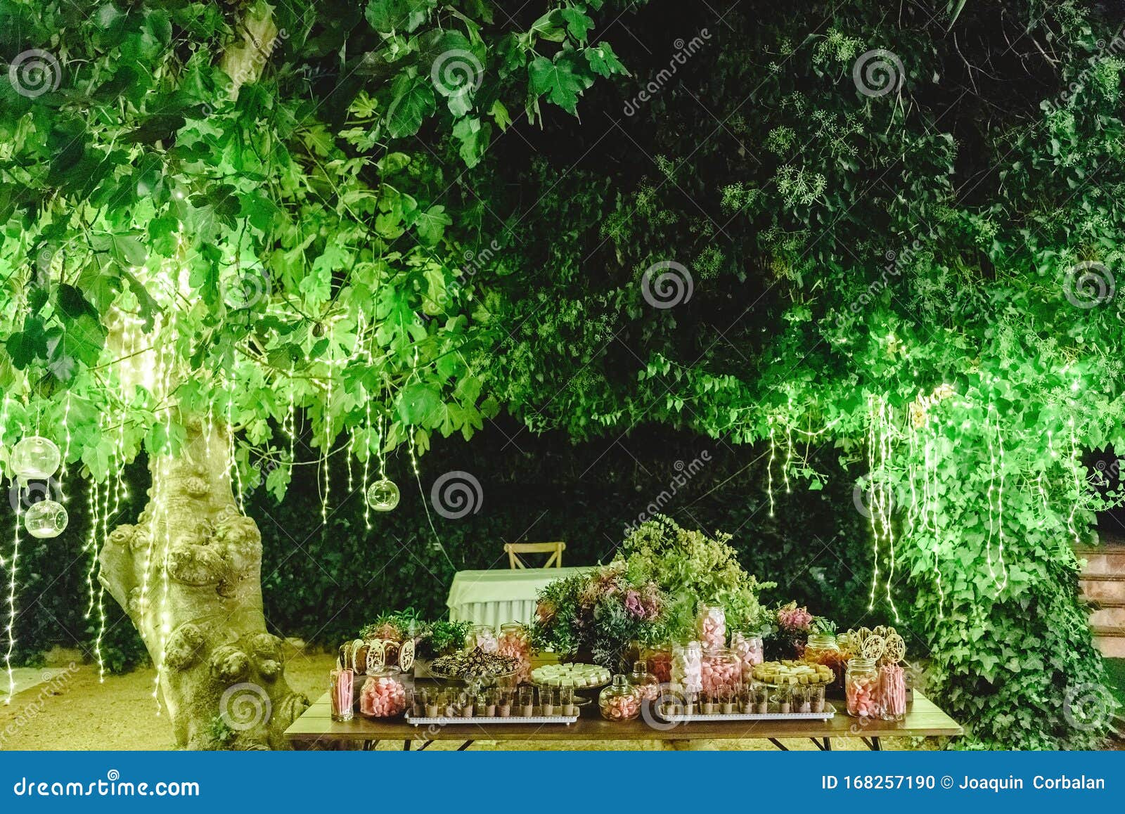 table with sweet desserts in a garden at night, illuminated by led lights