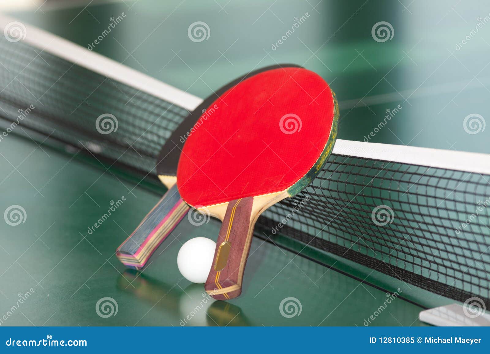 Table tennis rackets and ball. Two table tennis or ping pong rackets and balls on a green table with net