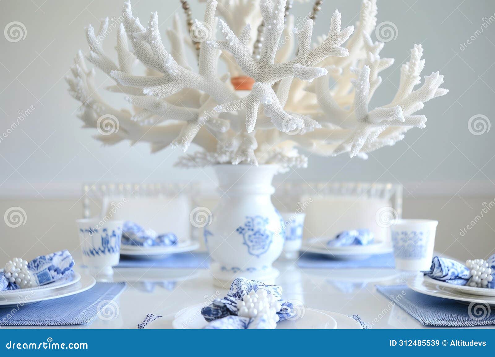 table with a white coral chandelier above, bluewhite porcelain, and pearl napkin rings