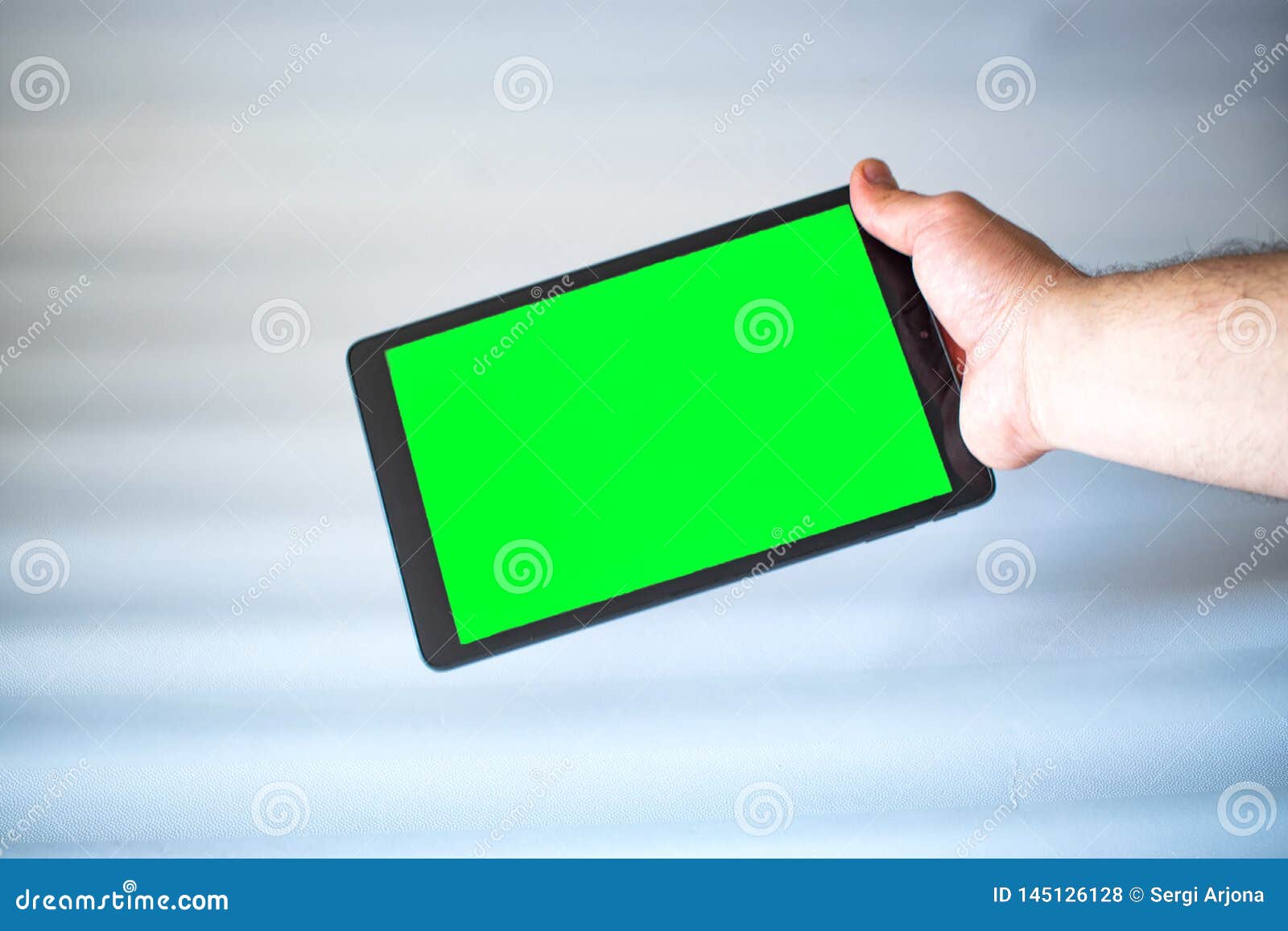 Tablet with Green Screen Fastened with One Hand on White Background