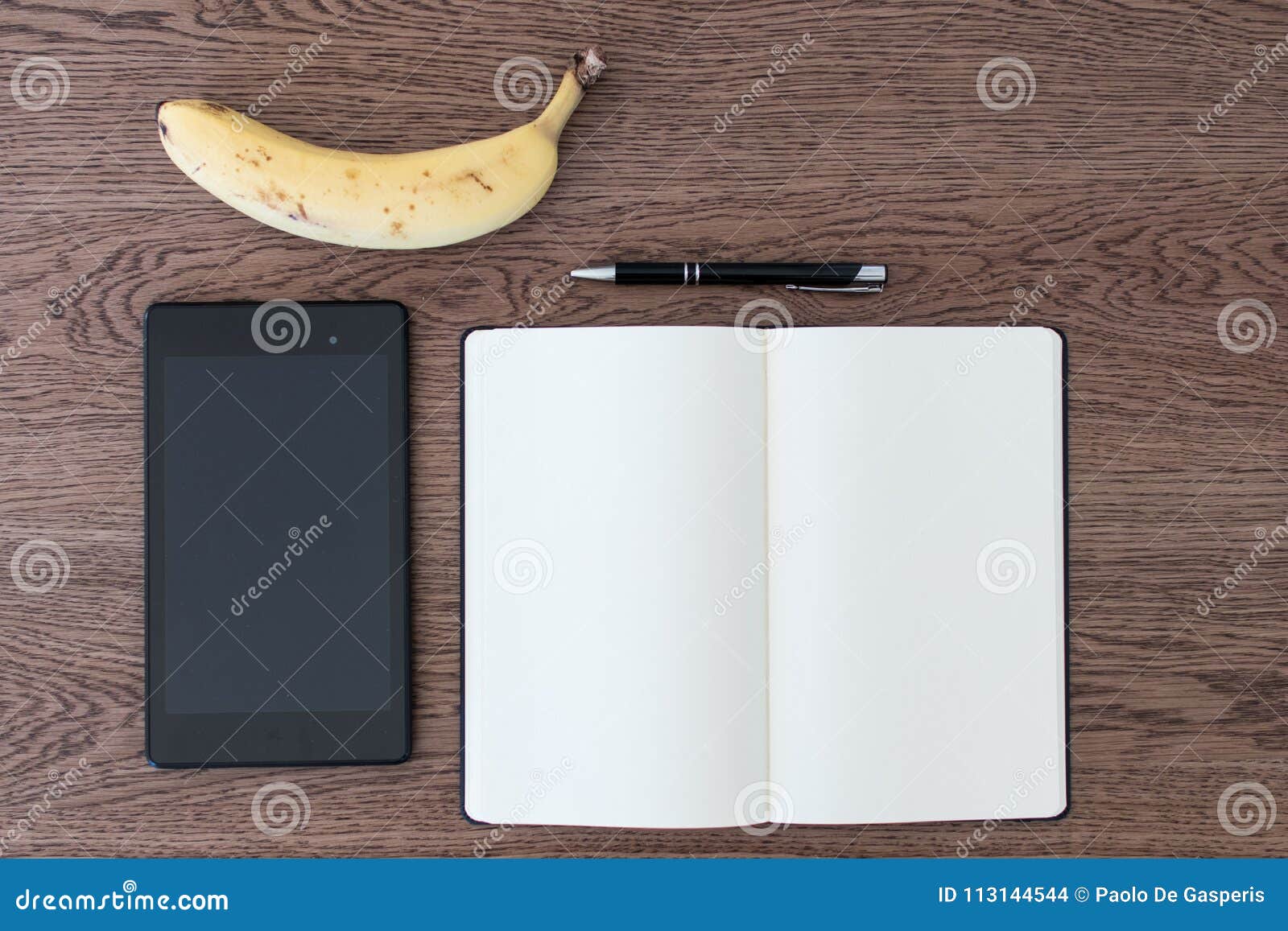 tablet, notebook, pen and a banana on a wooden table. image concept for journalism, liar and fake news, problems of hoaxes and tr