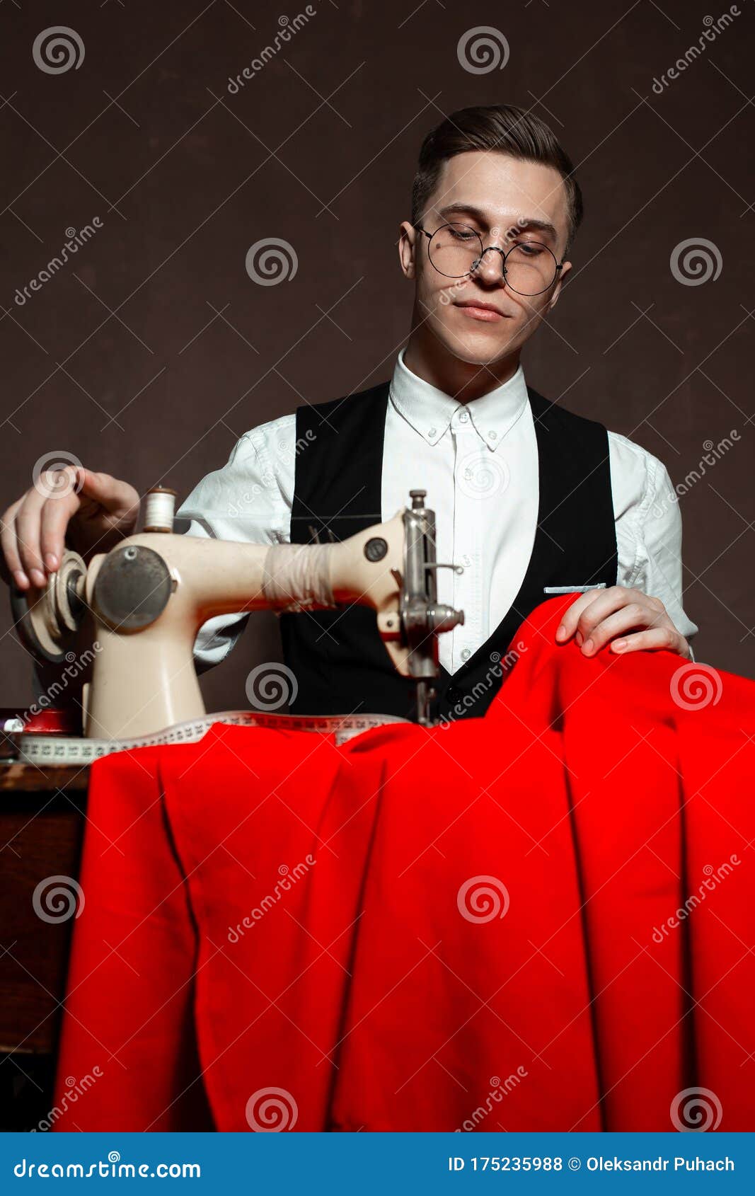Tailor in Round Glasses Sits at a Table with a Sewing Machine Stock